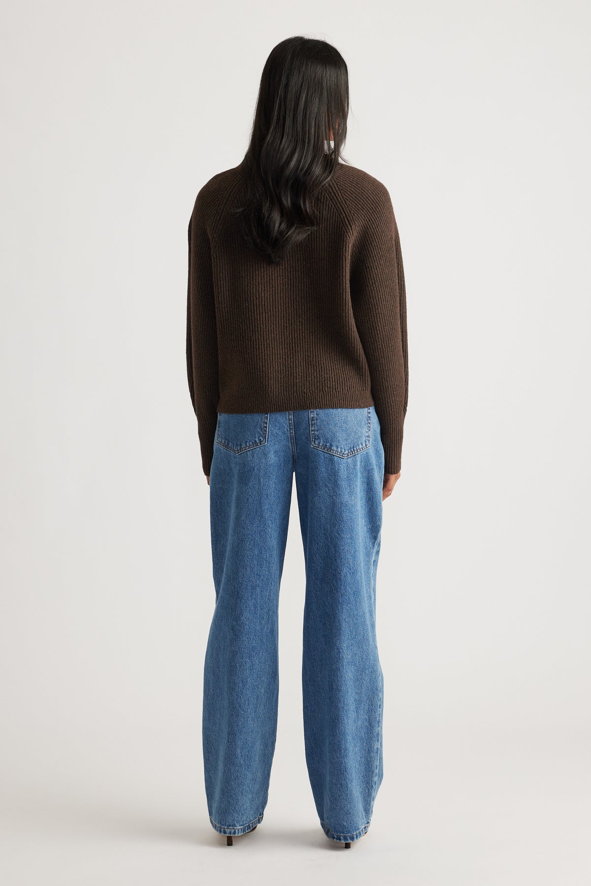 Woman wearing a cozy brown knit cardigan paired with relaxed fit mid-blue wide-leg denim jeans for casual style