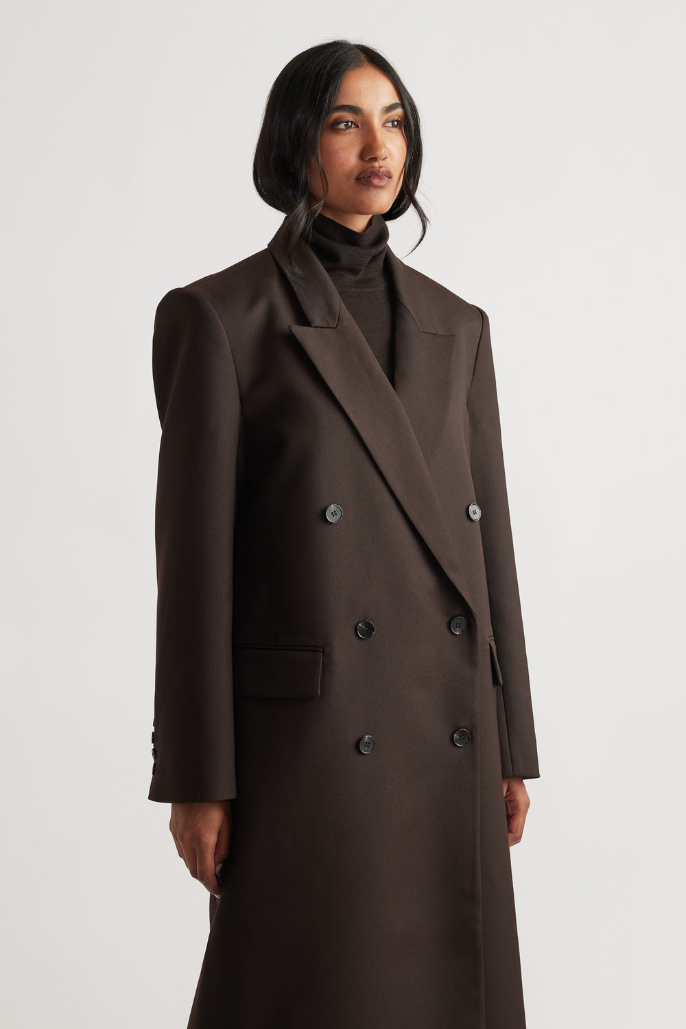 Woman wearing Ella Blazer Coat in rich brown, featuring double-breasted design and wide lapels with structured shoulder silhouette