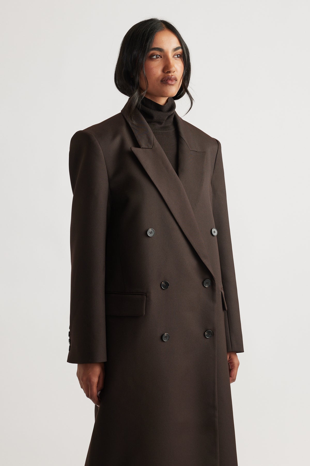 Woman wearing Ella Blazer Coat in rich brown, featuring double-breasted design and wide lapels with structured shoulder silhouette