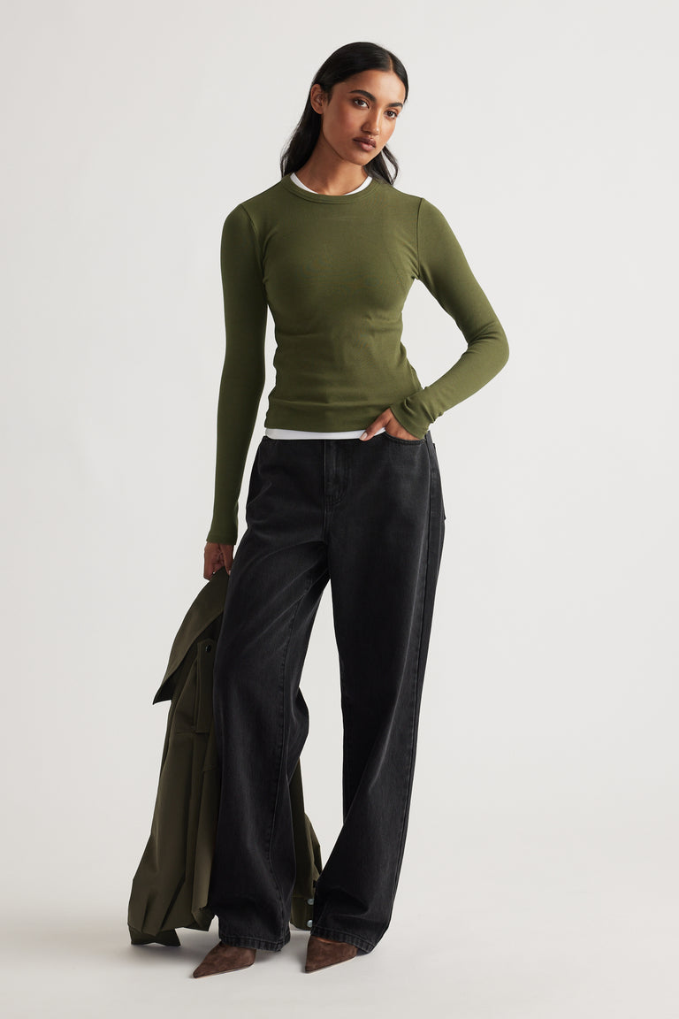 Slim fit olive long sleeve top layered over a white tee, styled with relaxed black wide-leg jeans and brown pointed shoes