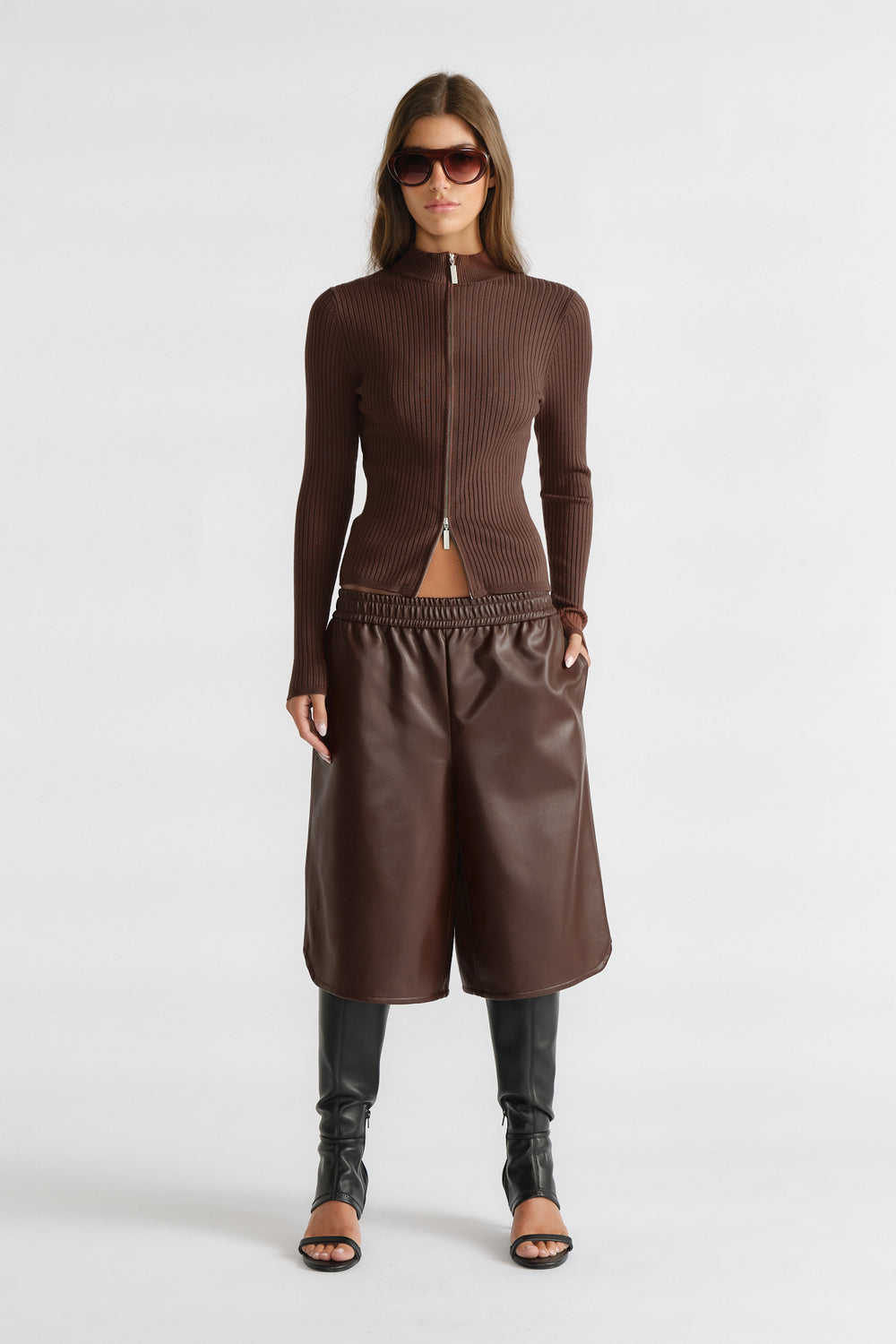 Woman wearing D-Luxe Knit Zip Long Sleeve in walnut brown rib knit with zip front, paired with leather culottes and tall black boots