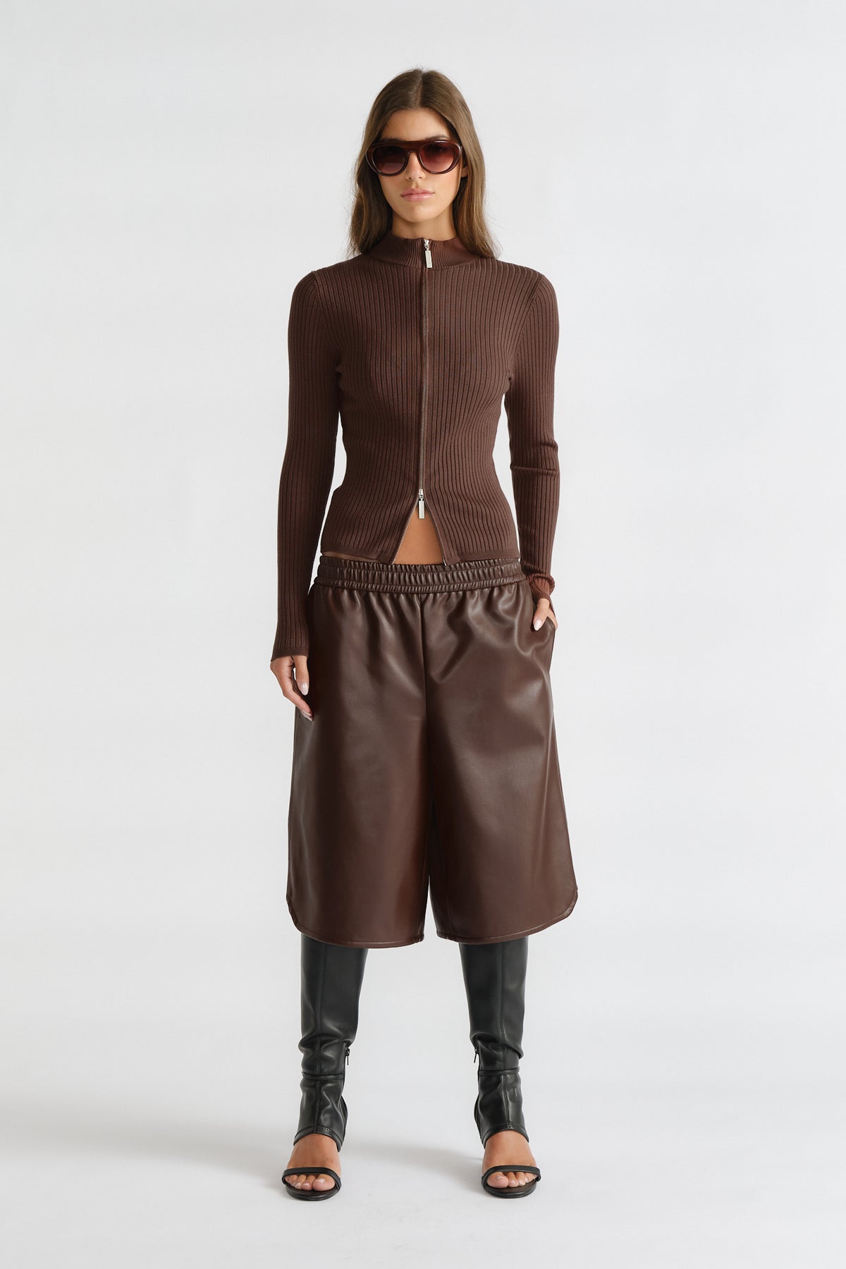 Woman wearing D-Luxe Knit Zip Long Sleeve in walnut brown rib knit with zip front, paired with leather culottes and tall black boots