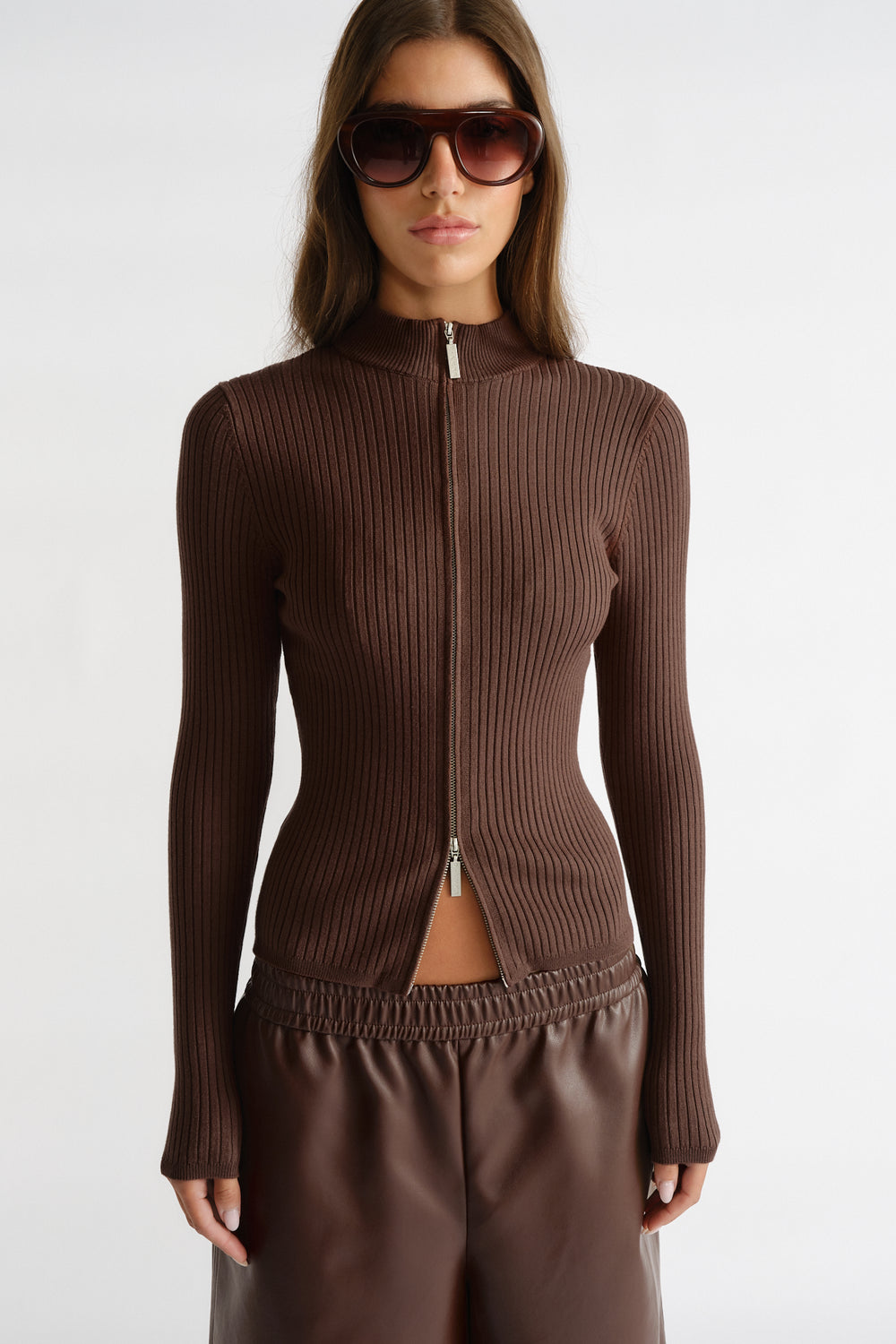 Woman wearing a fitted walnut brown D-Luxe Knit Zip Long Sleeve with vertical rib texture and silver zipper detail.