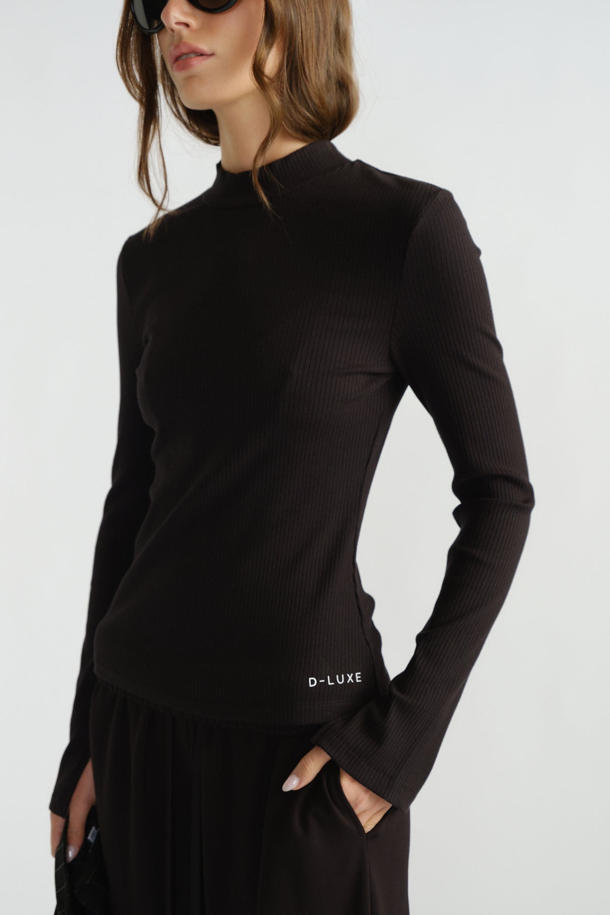 Close-up of a sleek black ribbed long sleeve top with a subtle high neckline and fitted silhouette.