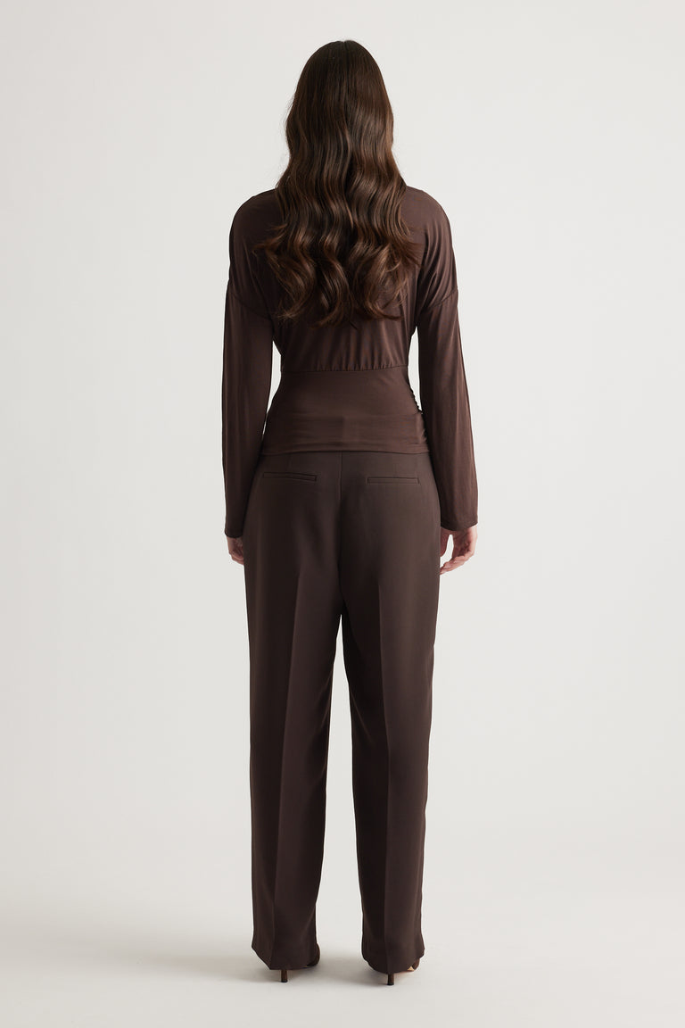 Woman wearing a fitted brown long sleeve top paired with matching tailored trousers for a sleek, polished look