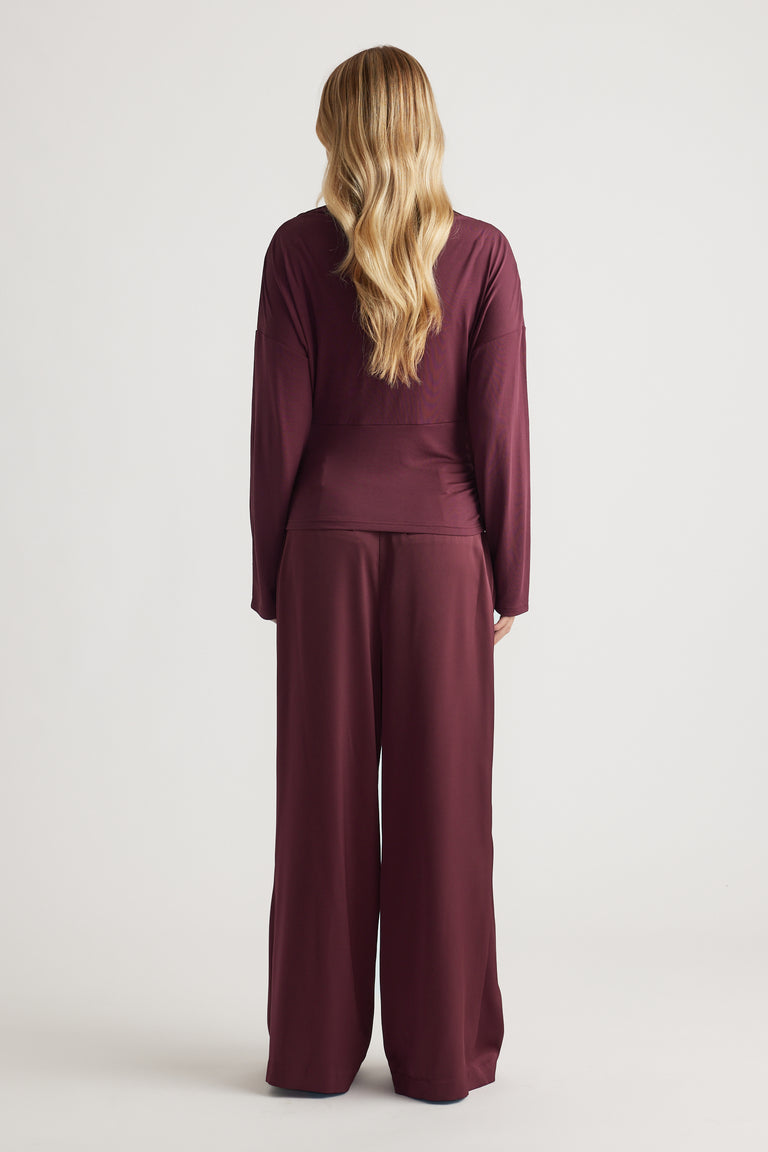 Back view of a woman wearing a plum cinched long sleeve top paired with matching wide-leg pants for a relaxed look