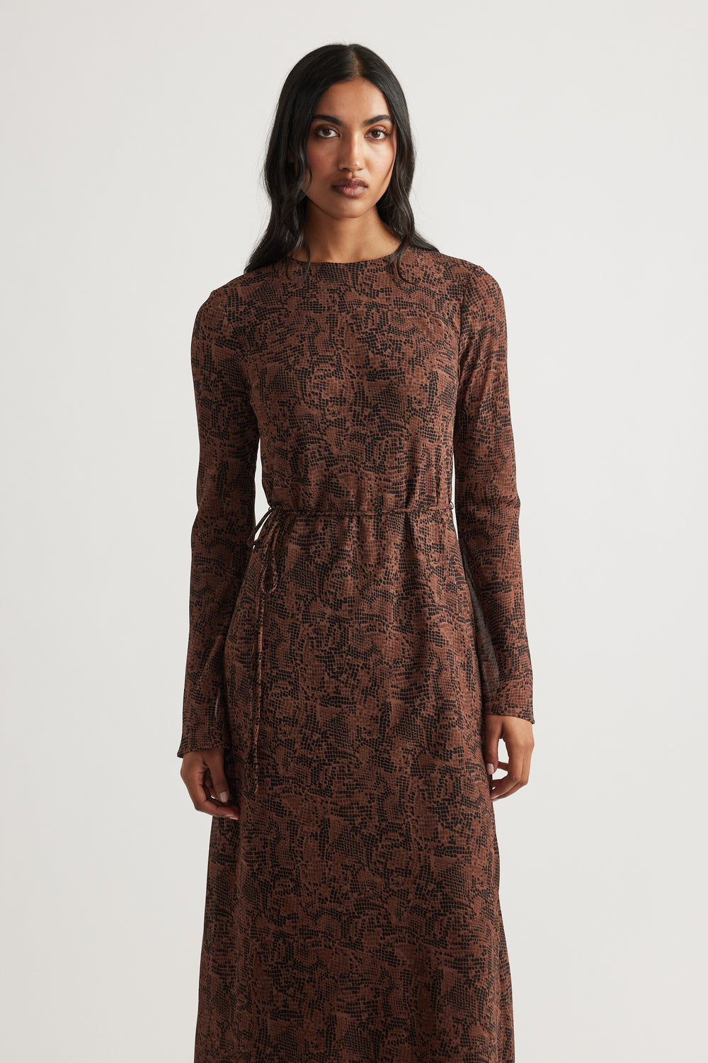 Woman wearing a long-sleeve brown snake print maxi dress with a cinched waist for a sleek, modern look