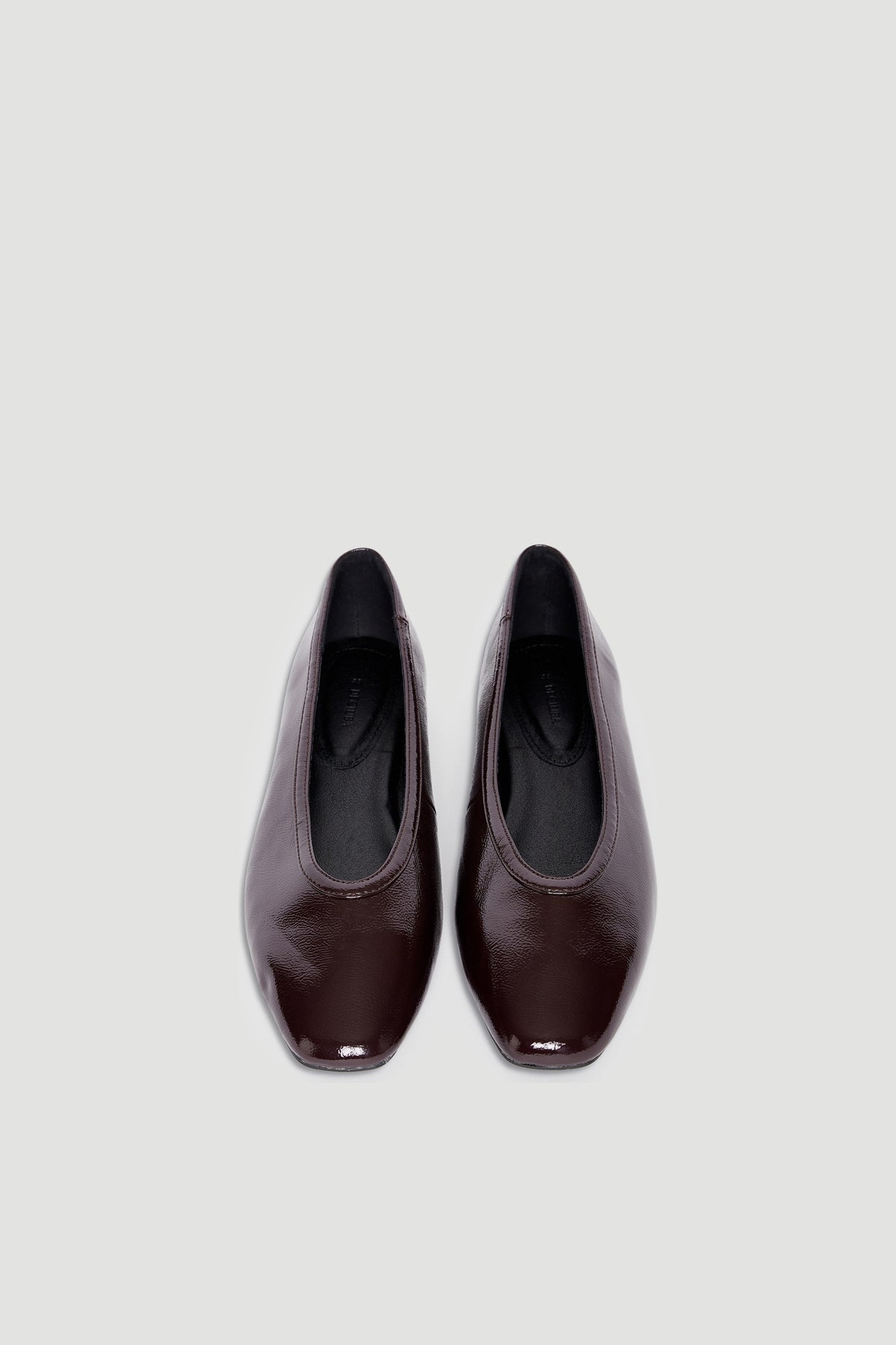 Pair of glossy dark brown square-toe ballet flats with smooth finish on neutral background