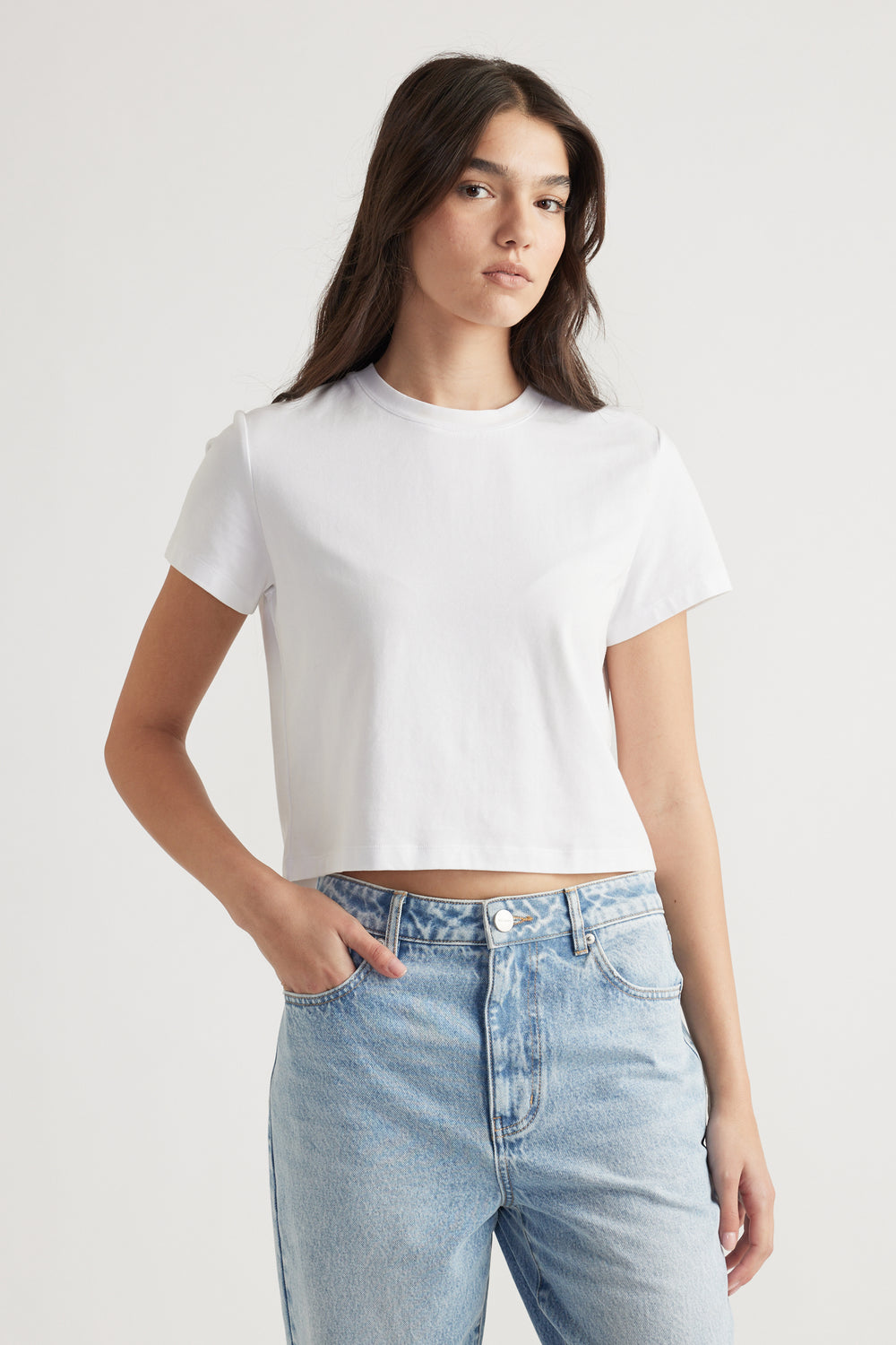 Woman wearing a bright white cropped tee paired with high-rise light wash denim jeans for a fresh casual look.