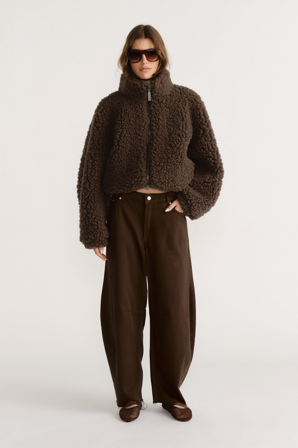 Woman wearing a cropped brown textured jacket with wide-leg dark brown pants and brown pointed flats