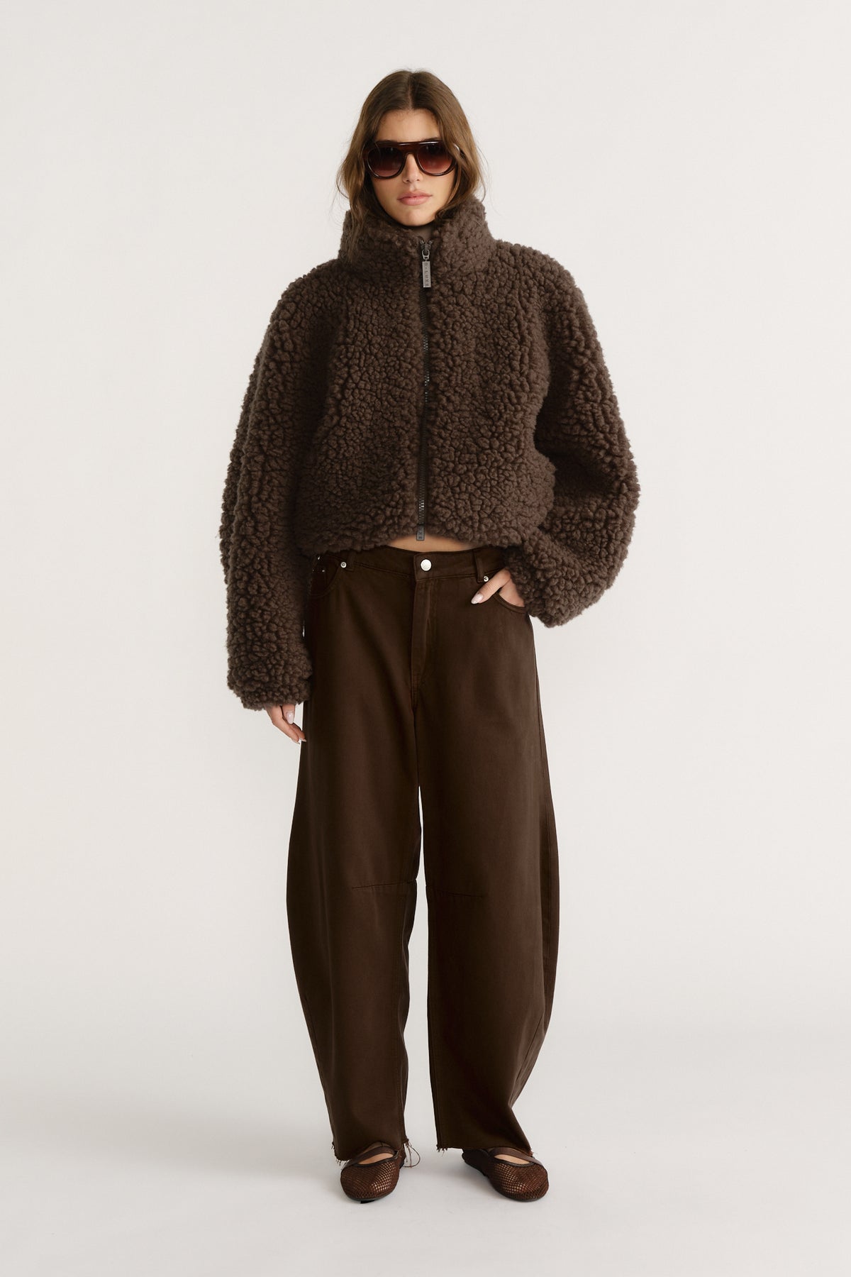 Woman wearing a cropped brown textured jacket with wide-leg dark brown pants and brown pointed flats
