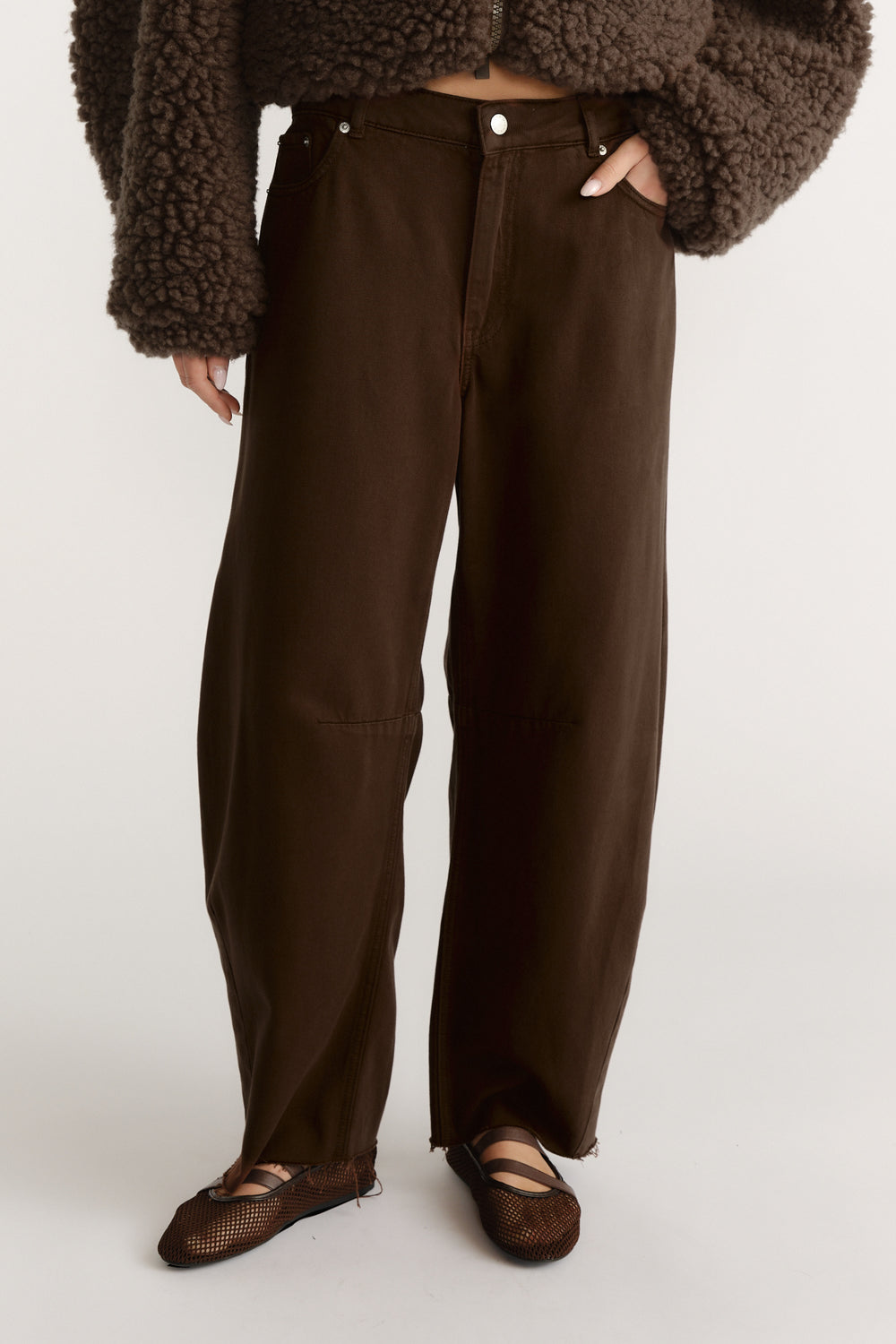 High-waist wide-leg brown jeans paired with a textured dark brown cropped jacket and mesh ballet flats