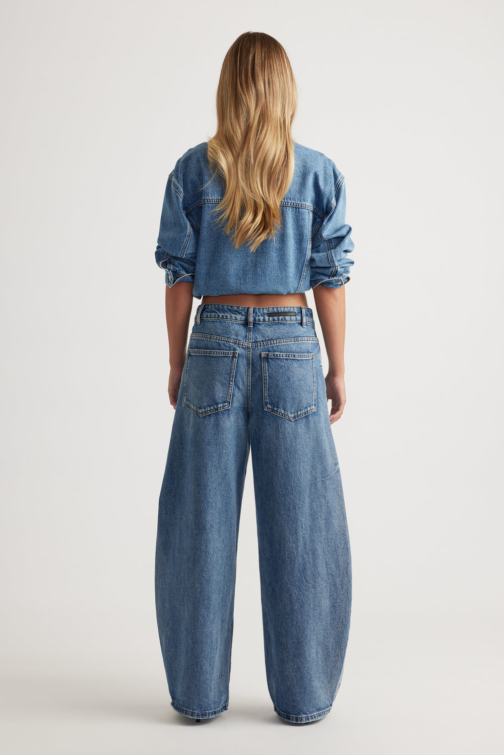Woman wearing a cropped denim jacket with high rise horseshoe leg jeans