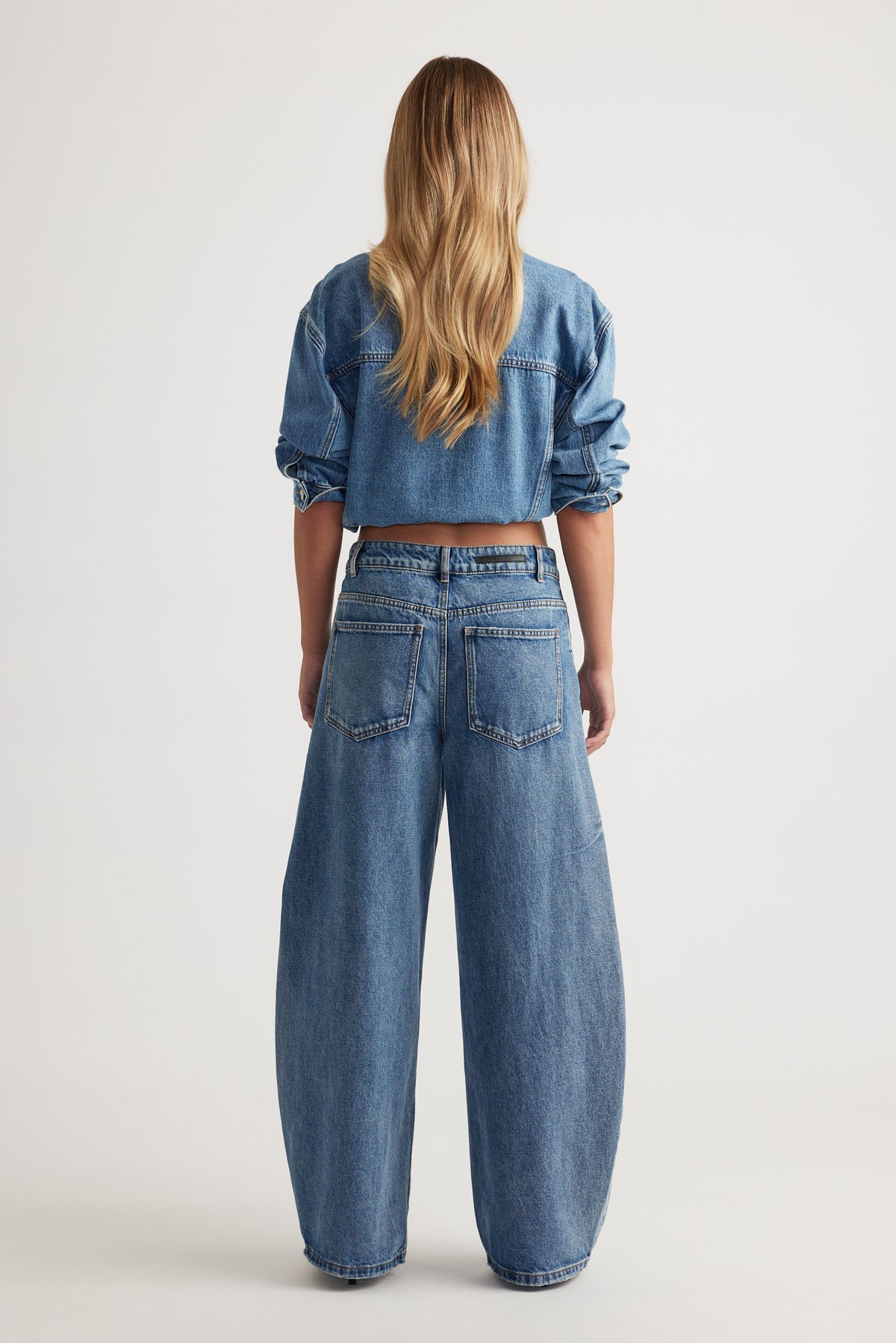 Woman wearing a cropped denim jacket with high rise horseshoe leg jeans