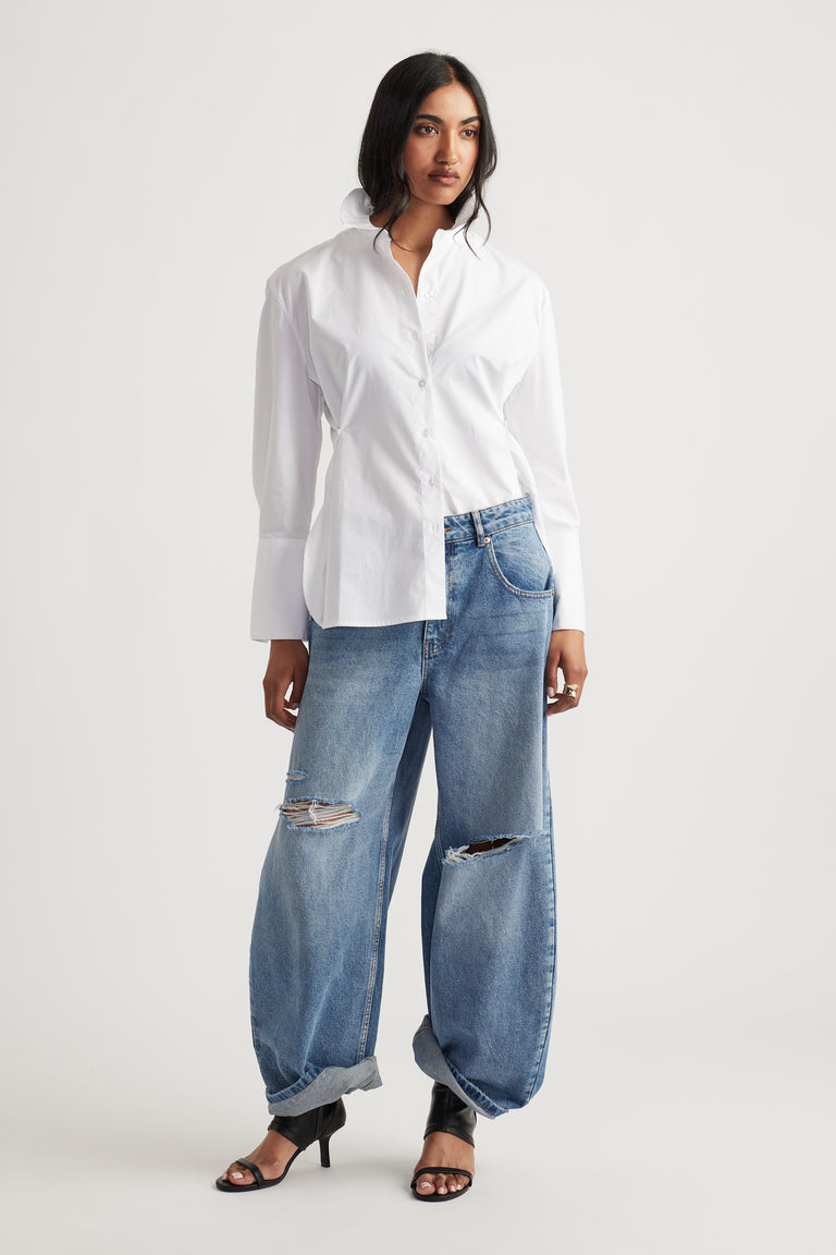 Model wearing a white button-up shirt with distressed wide-leg horseshoe jeans and black heels