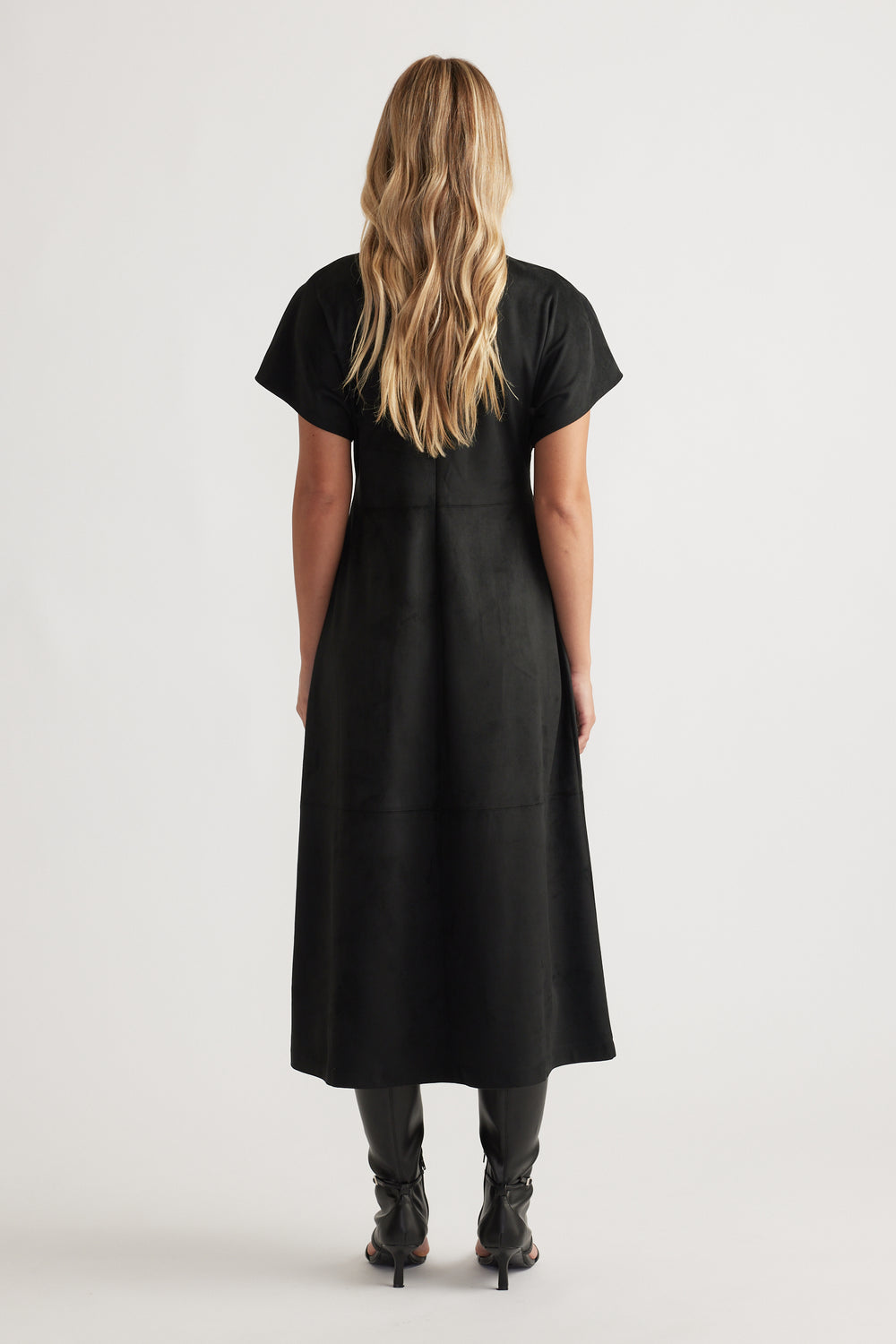 Back view of Clara Faux Suede Midi Dress in sleek black with short sleeves, styled with black heeled boots for a modern look