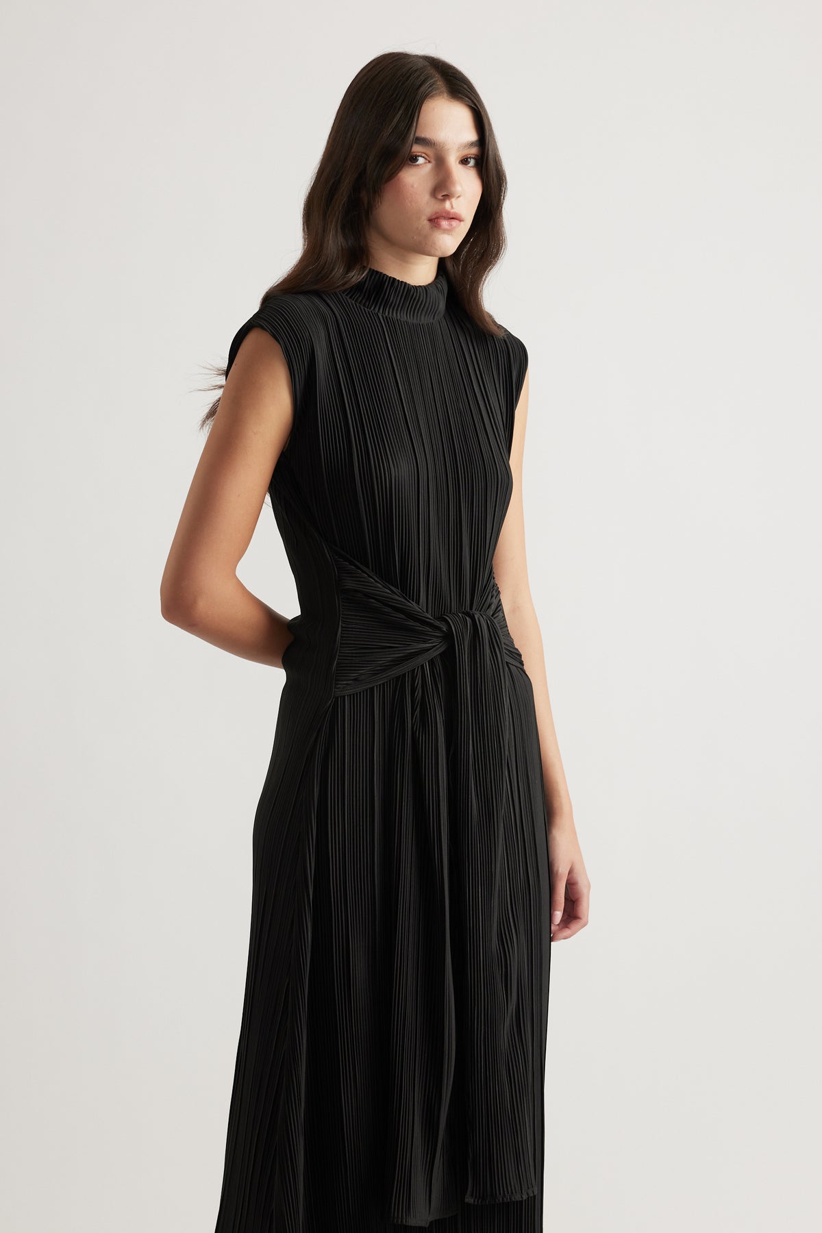 Sleeveless black pleated maxi dress with a high neck and tie waist detail for elegant everyday wear