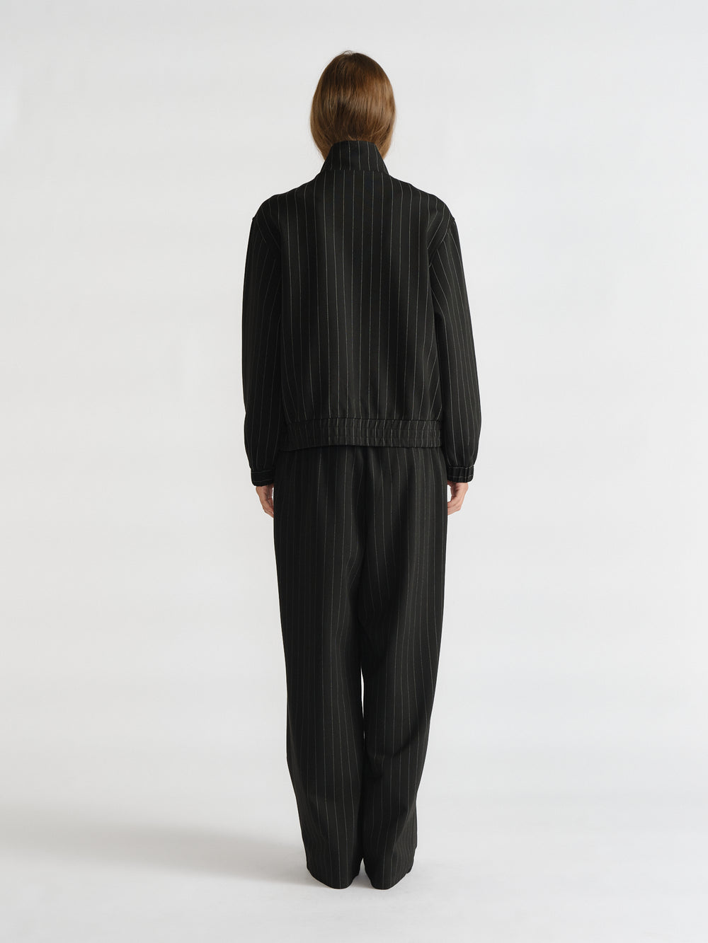 Rear view of woman in relaxed D-Luxe Pinstripe Bomber and matching wide-leg pants for a sleek, timeless look by Decjuba.