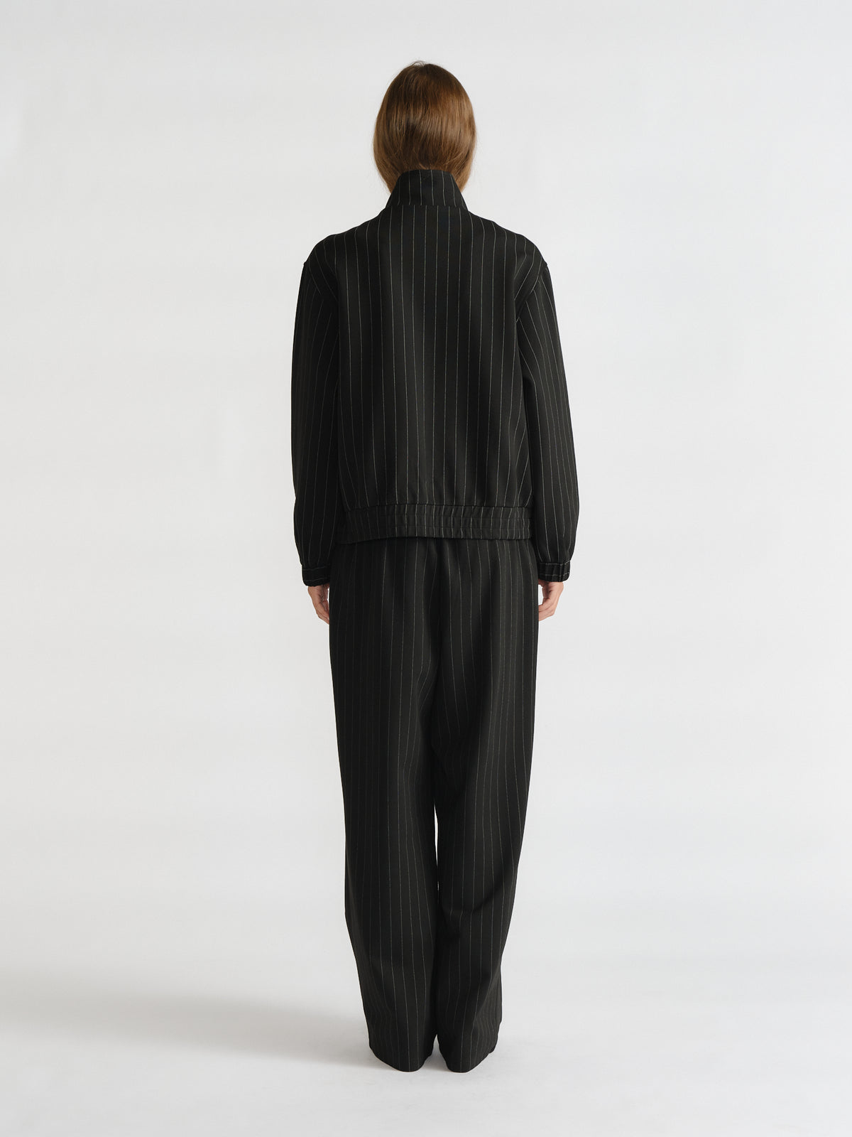 Rear view of woman in relaxed D-Luxe Pinstripe Bomber and matching wide-leg pants for a sleek, timeless look by Decjuba.