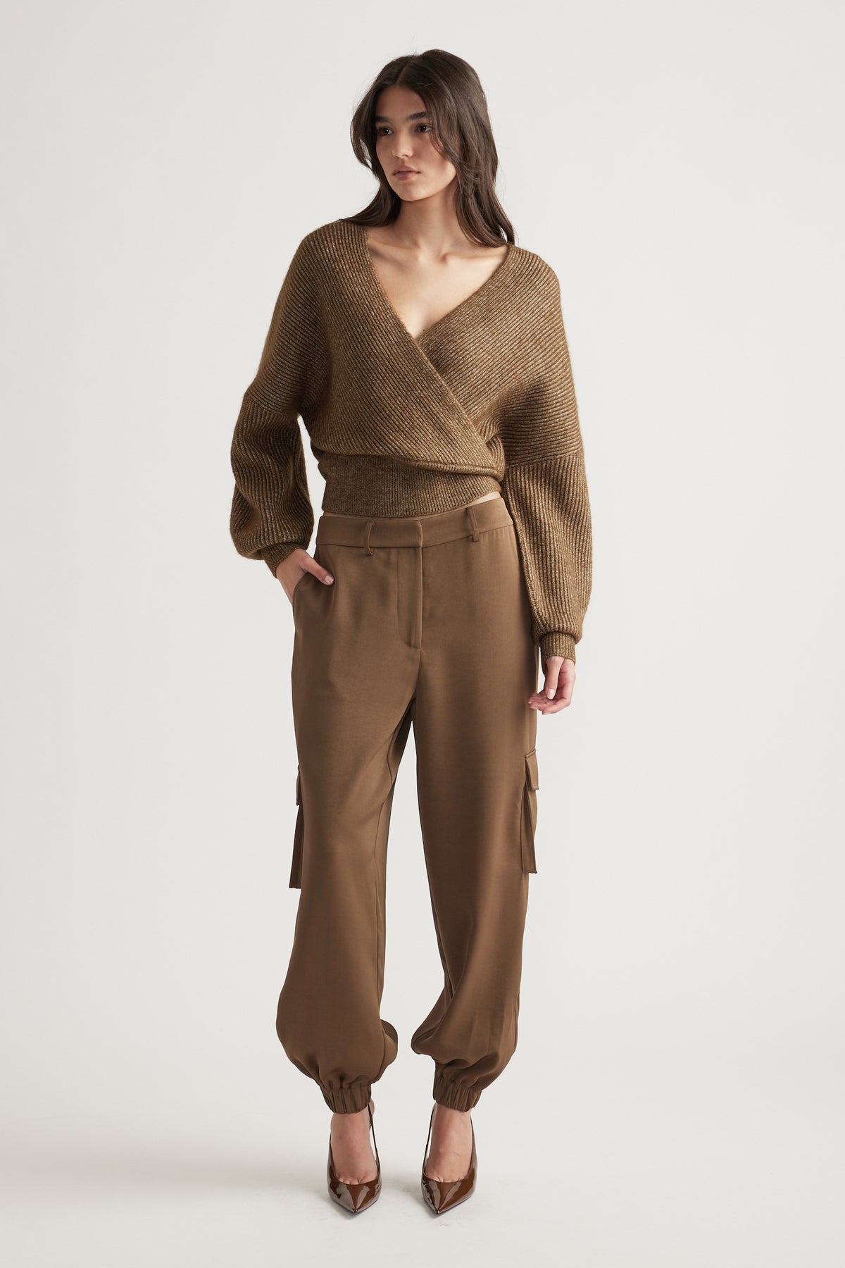 Woman wearing a bronze crossover knit jumper styled with high-waisted cargo pants and brown pointed heels