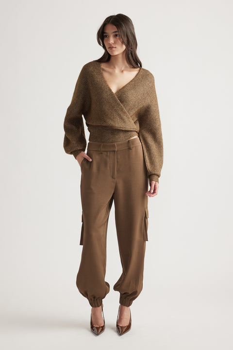 Woman wearing a bronze crossover knit jumper styled with high-waisted cargo pants and brown pointed heels