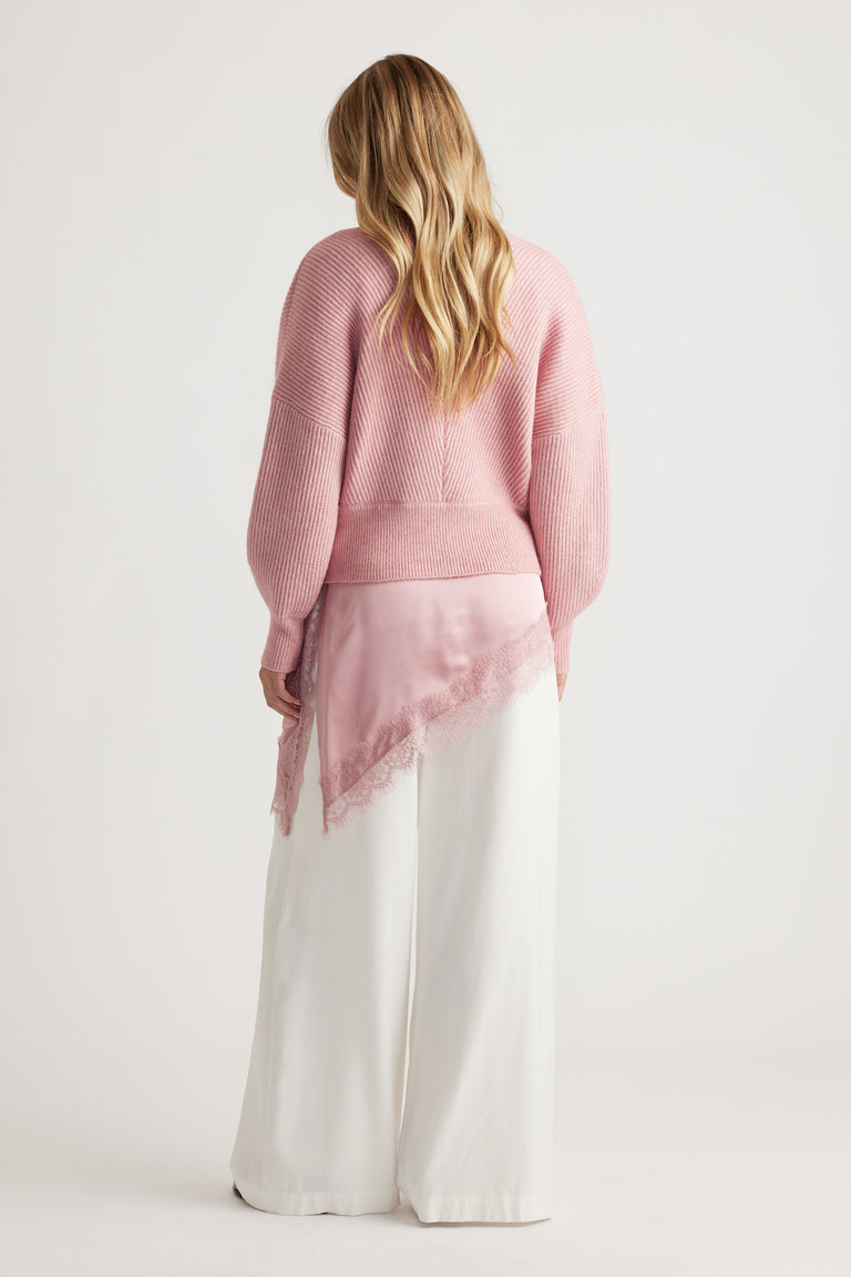 Soft pink ribbed jumper paired with wide-leg white pants and a delicate lace-trimmed silk scarf for a feminine touch.