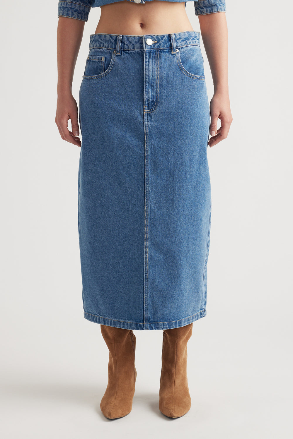 Mid-blue denim midi skirt with classic five-pocket design styled with tan suede boots for a timeless look