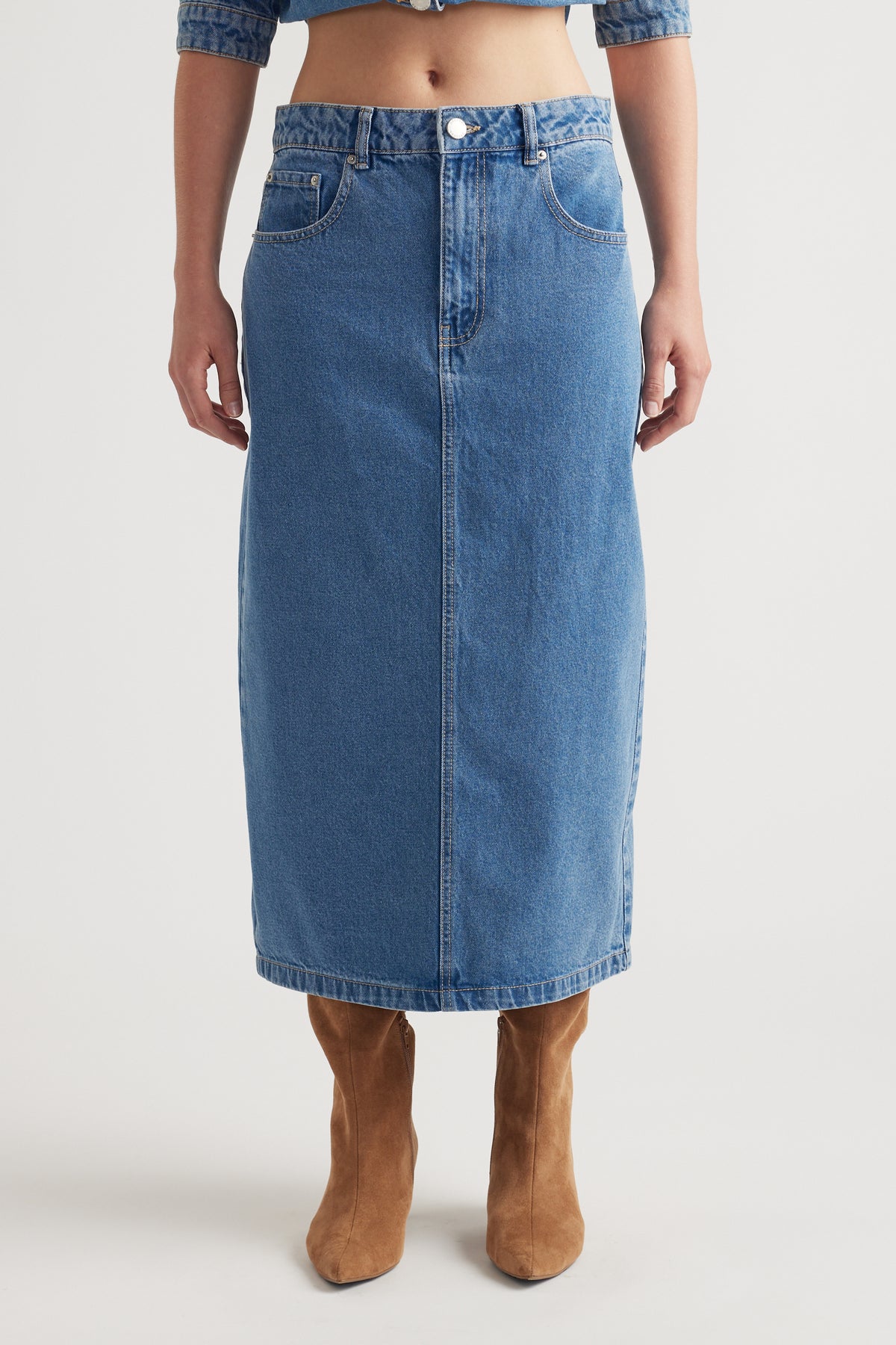 Mid-blue denim midi skirt with classic five-pocket design styled with tan suede boots for a timeless look
