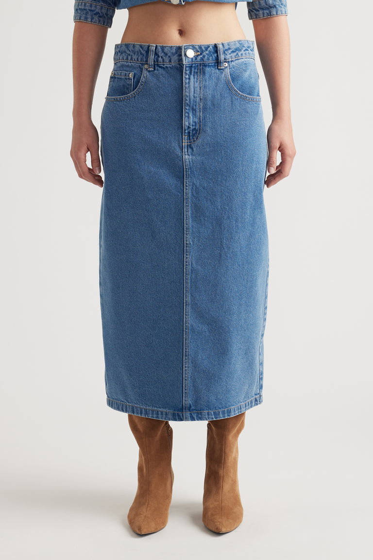 Mid-blue denim midi skirt with classic five-pocket design styled with tan suede boots for a timeless look