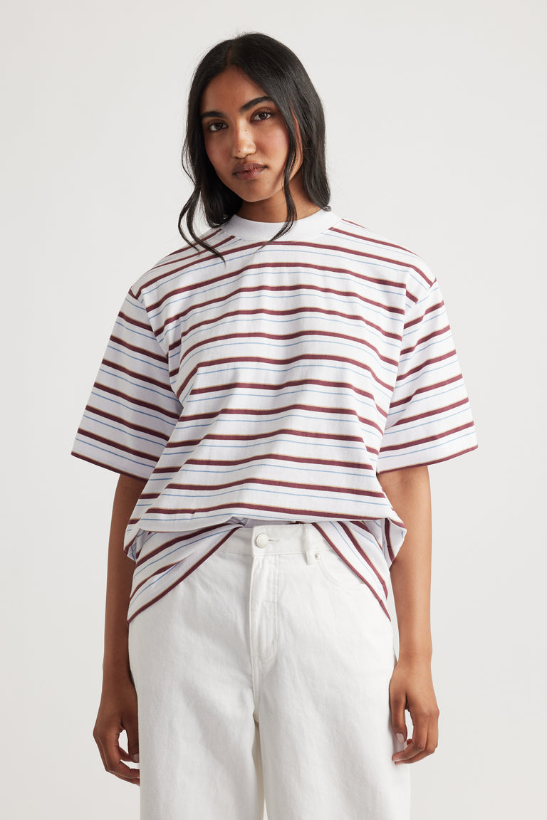 Woman wearing Isabella Oversized Stripe Tee in white with maroon and blue stripes, paired with relaxed white pants by DECJUBA