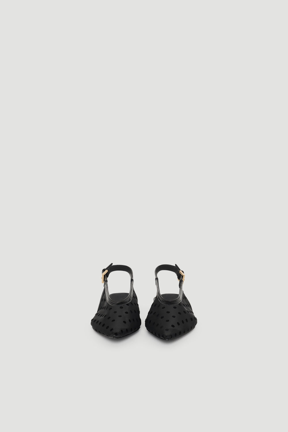 Black slingback flats with pointed toe and subtle polka dot texture, featuring an adjustable buckle strap for a chic finish