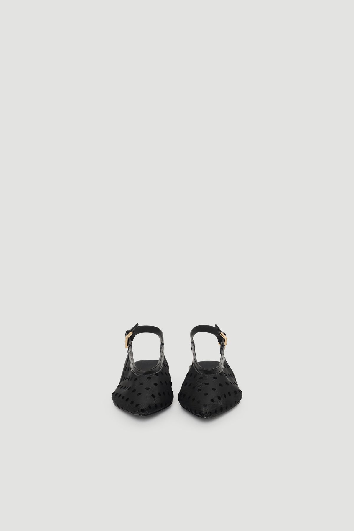 Black slingback flats with pointed toe and subtle polka dot texture, featuring an adjustable buckle strap for a chic finish