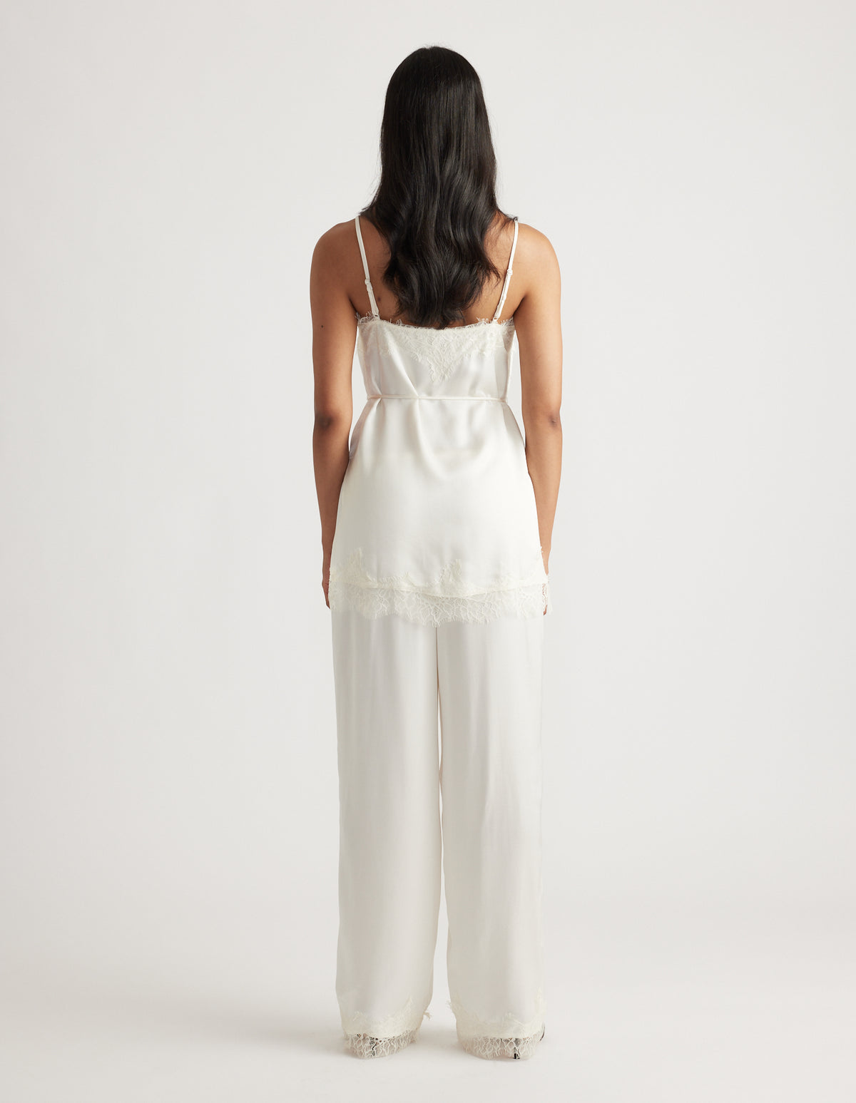 Back view of a white lace-trimmed camisole top paired with matching wide-leg pants in a relaxed fit.