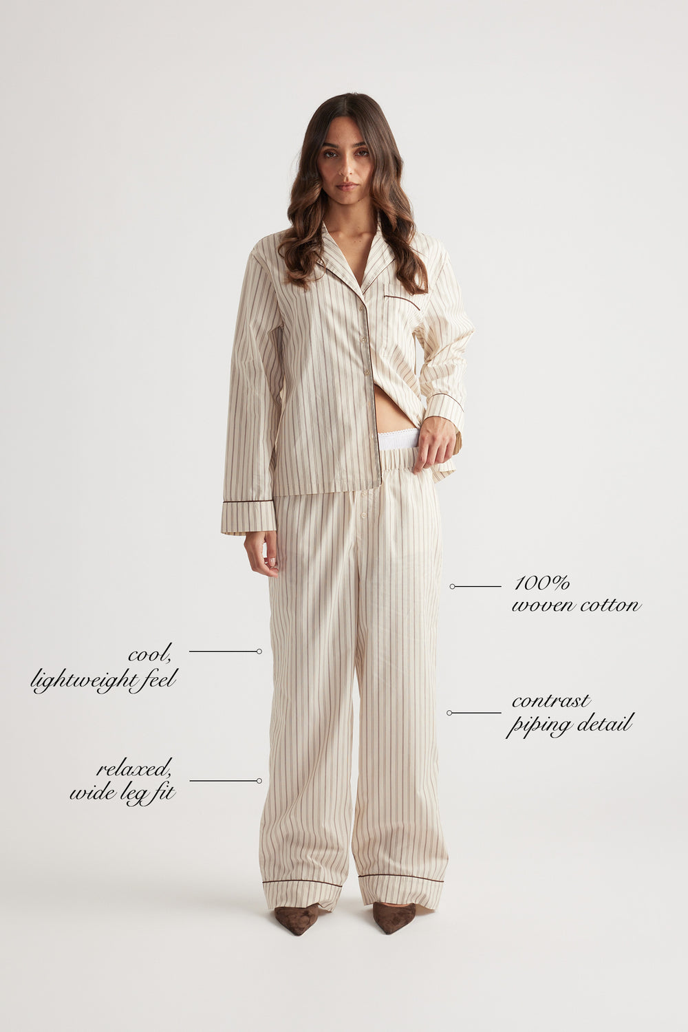 Woman wearing relaxed wide leg sleep pants in woven cotton with subtle vertical stripes and contrast piping trim