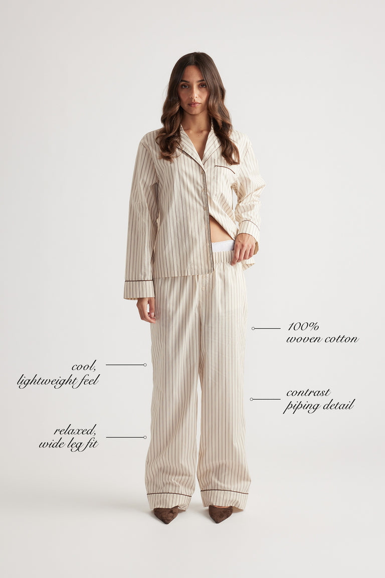 Woman wearing relaxed wide leg sleep pants in woven cotton with subtle vertical stripes and contrast piping trim