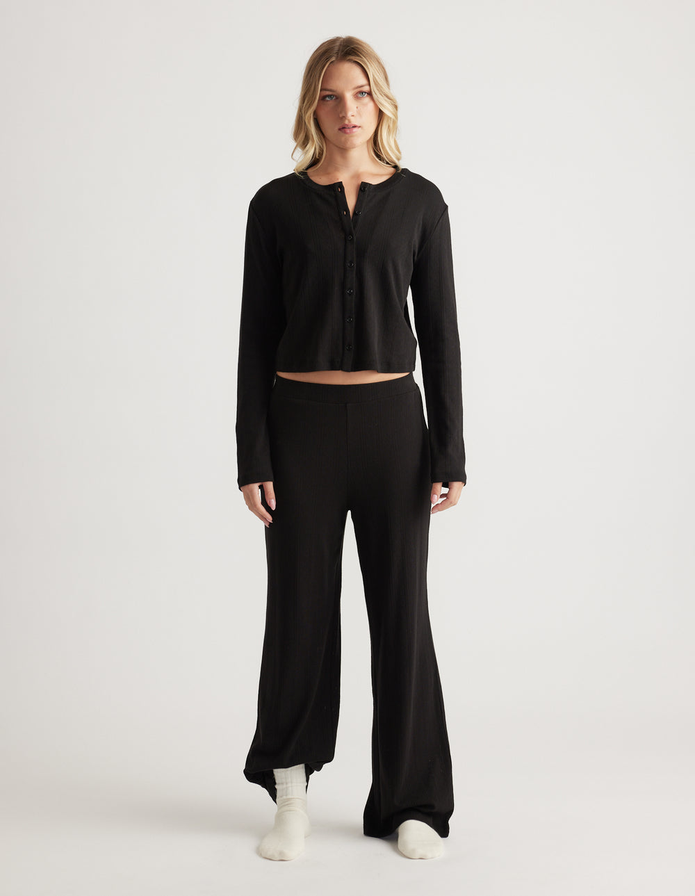 Woman wearing black sleep pointelle wide leg pants with a matching long sleeve button-up top in relaxed fit
