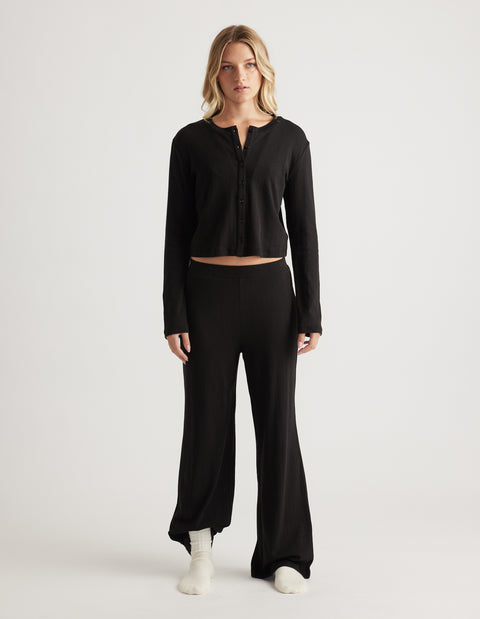 Woman wearing black sleep pointelle wide leg pants with a matching long sleeve button-up top in relaxed fit