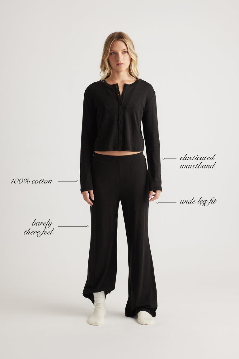 Woman wearing black wide leg pants with elastic waistband and matching long sleeve cropped top in soft cotton fabric