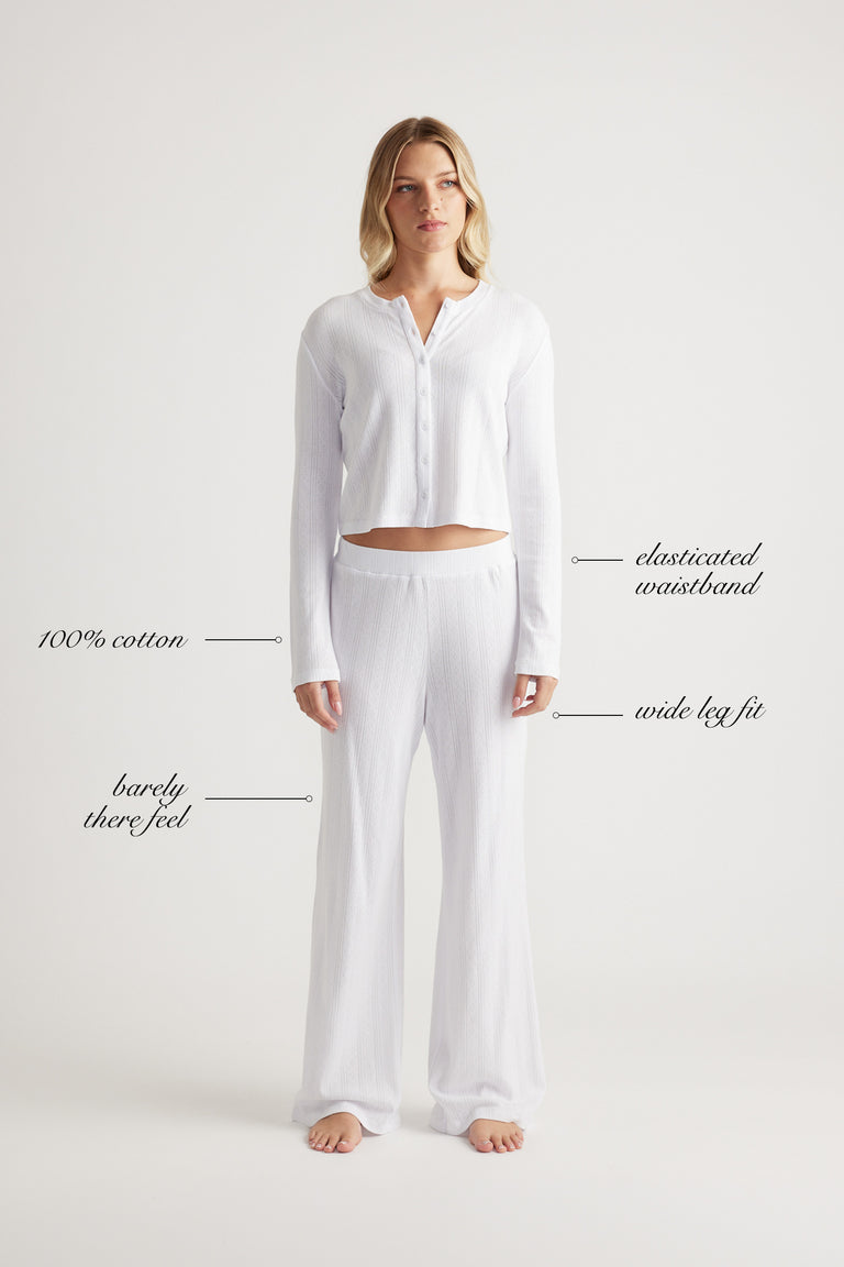 Woman wearing white cotton wide leg sleep pants with elastic waistband for a comfortable, lightweight fit