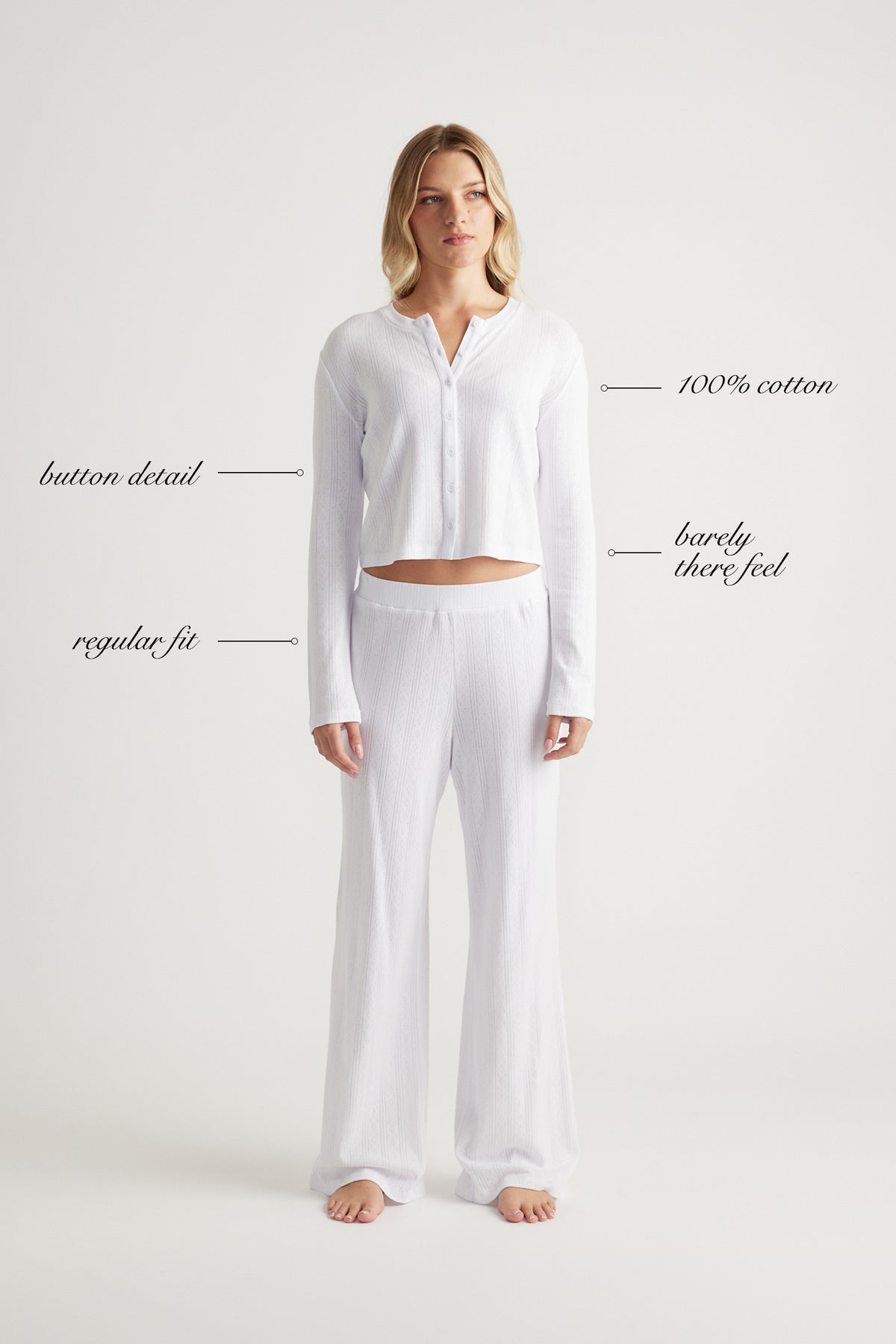 Woman wearing white cotton button-up top and matching wide-leg pants with relaxed fit standing barefoot