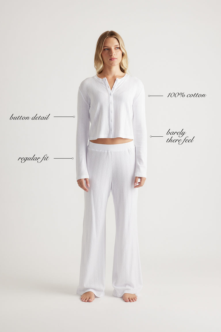 Woman wearing white cotton button-up top and matching wide-leg pants with relaxed fit standing barefoot
