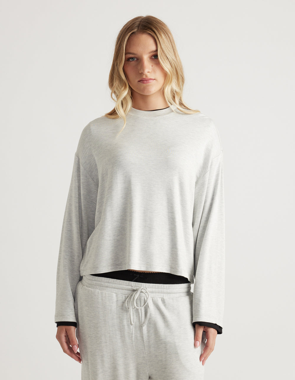 Woman wearing light grey relaxed fit long sleeve top paired with matching drawstring lounge pants