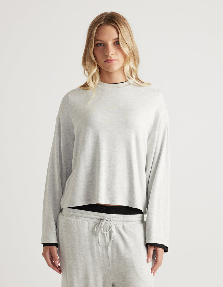 Woman wearing light grey relaxed fit long sleeve top paired with matching drawstring lounge pants