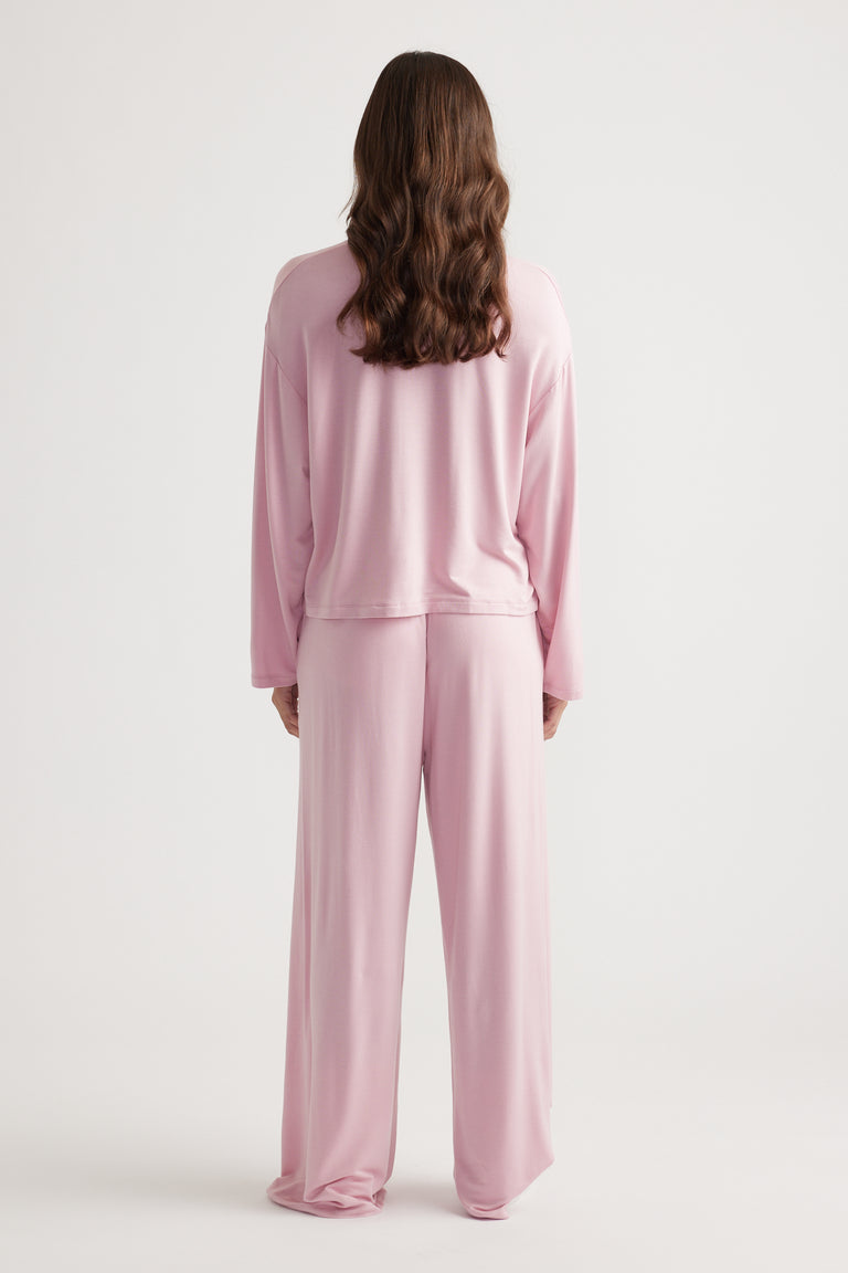Woman wearing a soft sleep jersey long sleeve top and matching wide leg pants in muted wildberry pink