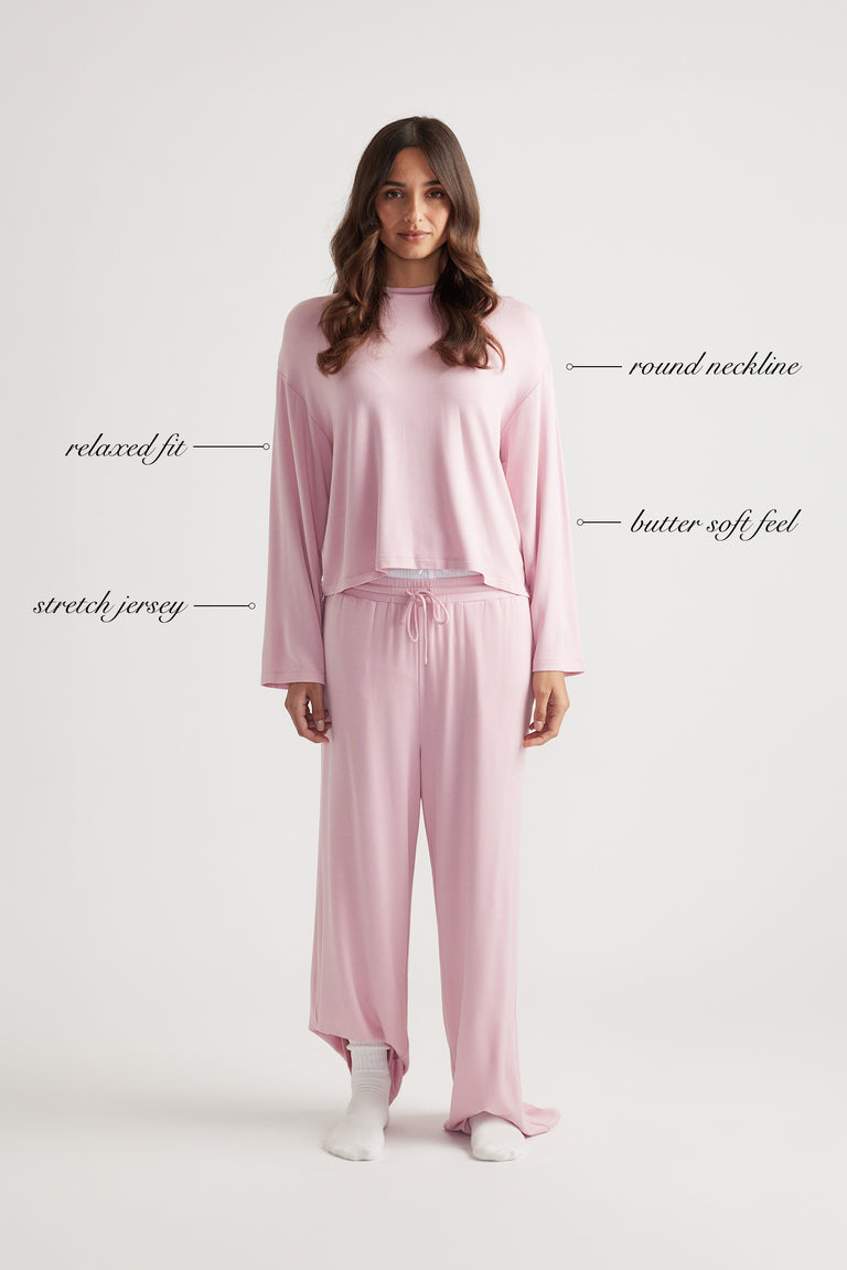 Woman wearing relaxed pink long sleeve sleep top and wide leg pants in soft stretch jersey for cozy comfort