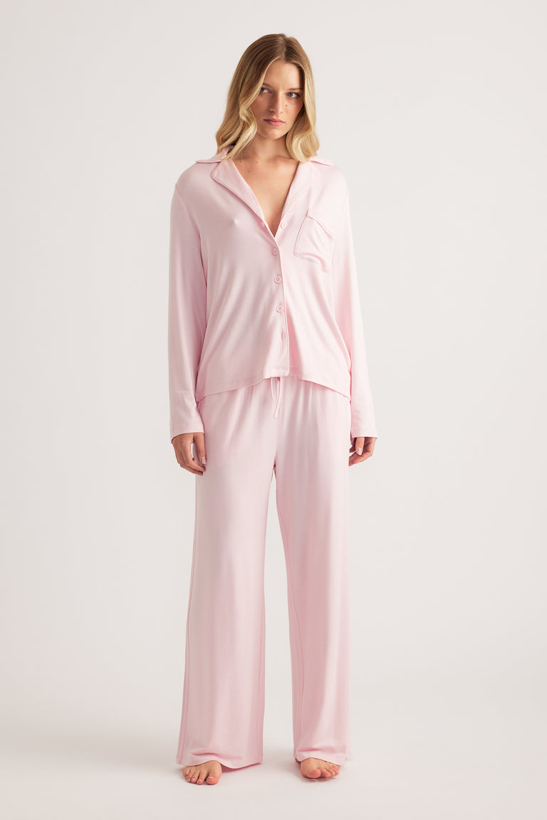 Woman in a pale pink button front sleepwear shirt with matching wide leg pants