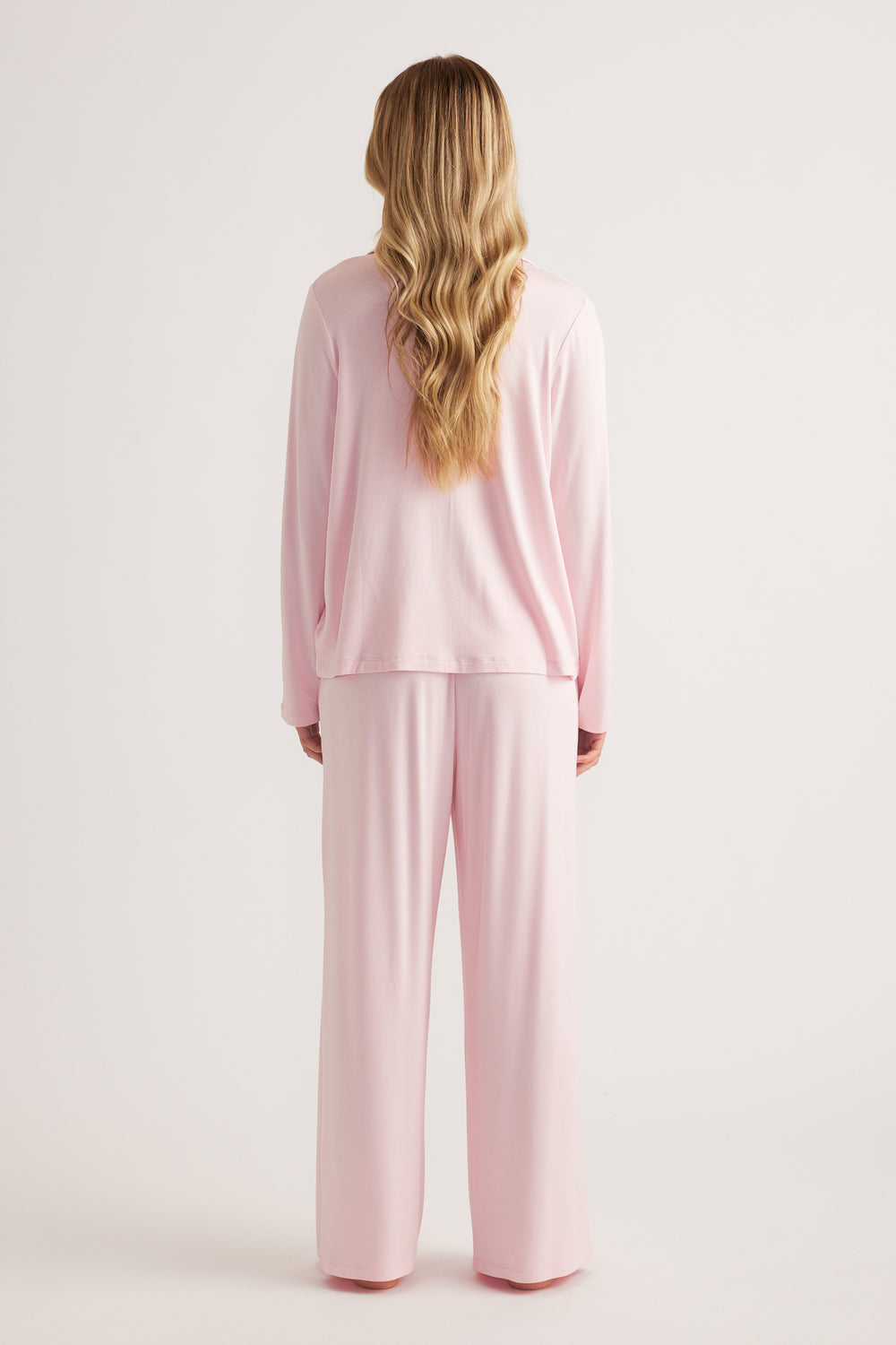 Woman wearing a soft pink long-sleeve sleep shirt with matching wide-leg pants