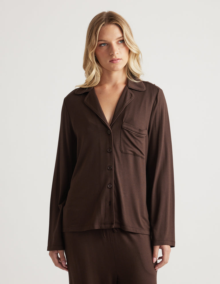 Woman wearing a relaxed fit dark brown button through shirt with a soft fabric and chest pocket detail