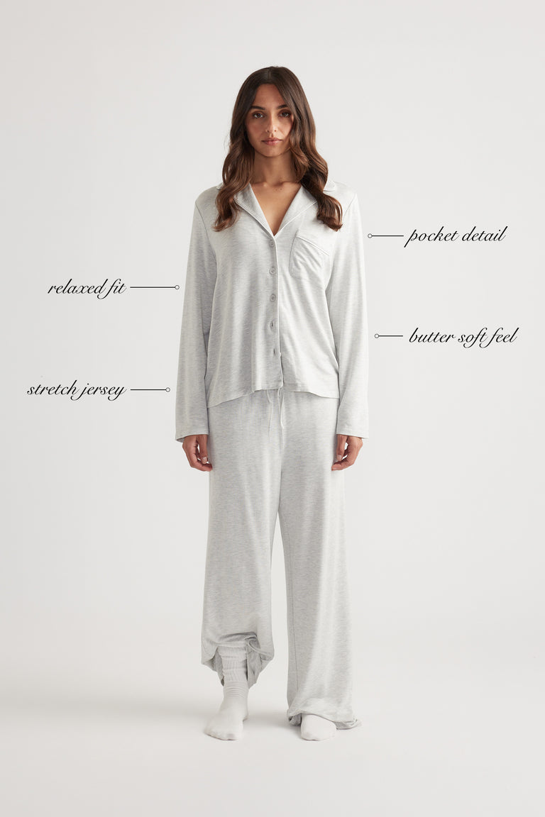 Woman wearing light grey sleep button through shirt with relaxed fit and matching wide leg pants in soft stretch jersey