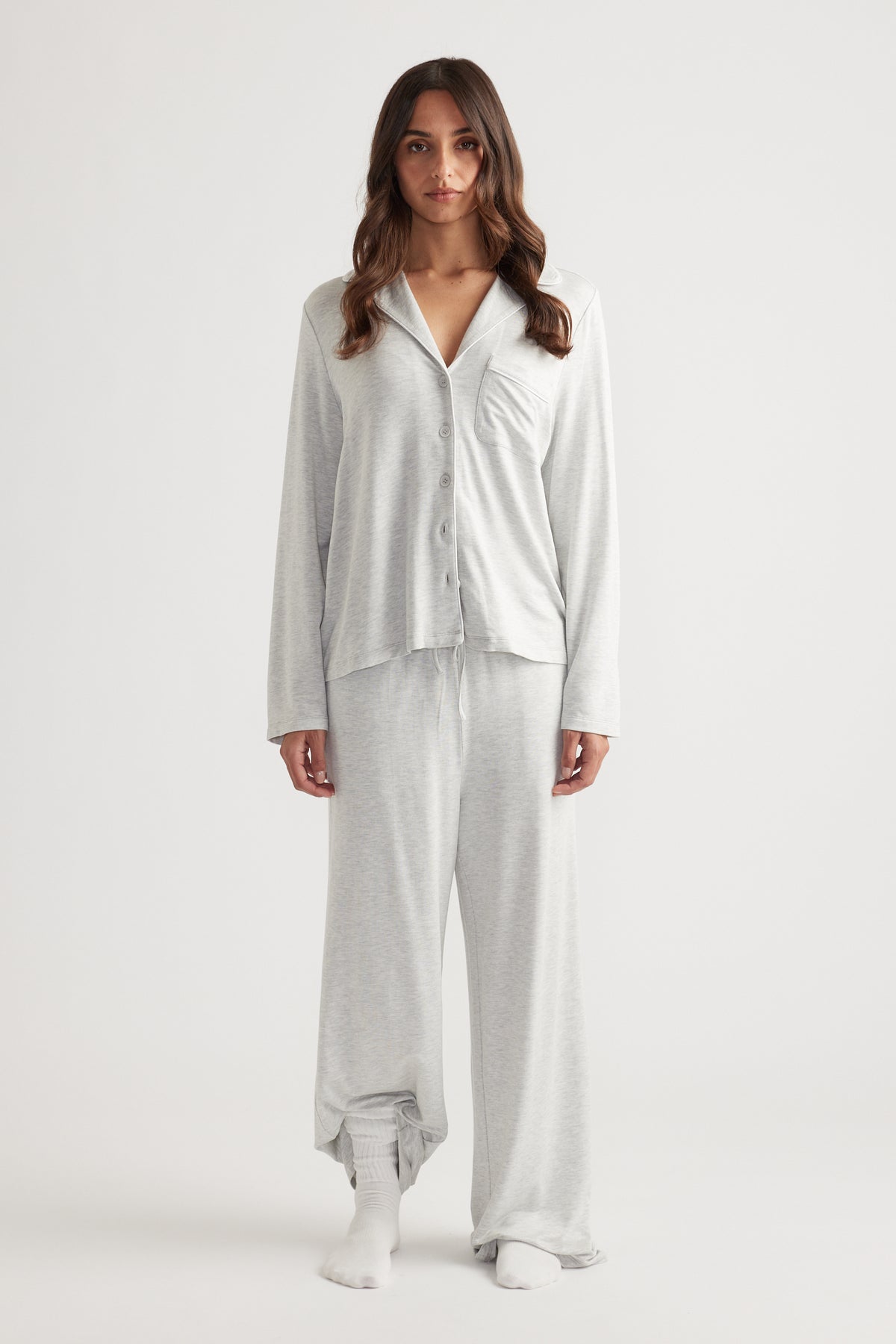 Woman wearing light grey sleep button through shirt with relaxed fit and matching wide leg lounge pants for easy comfort